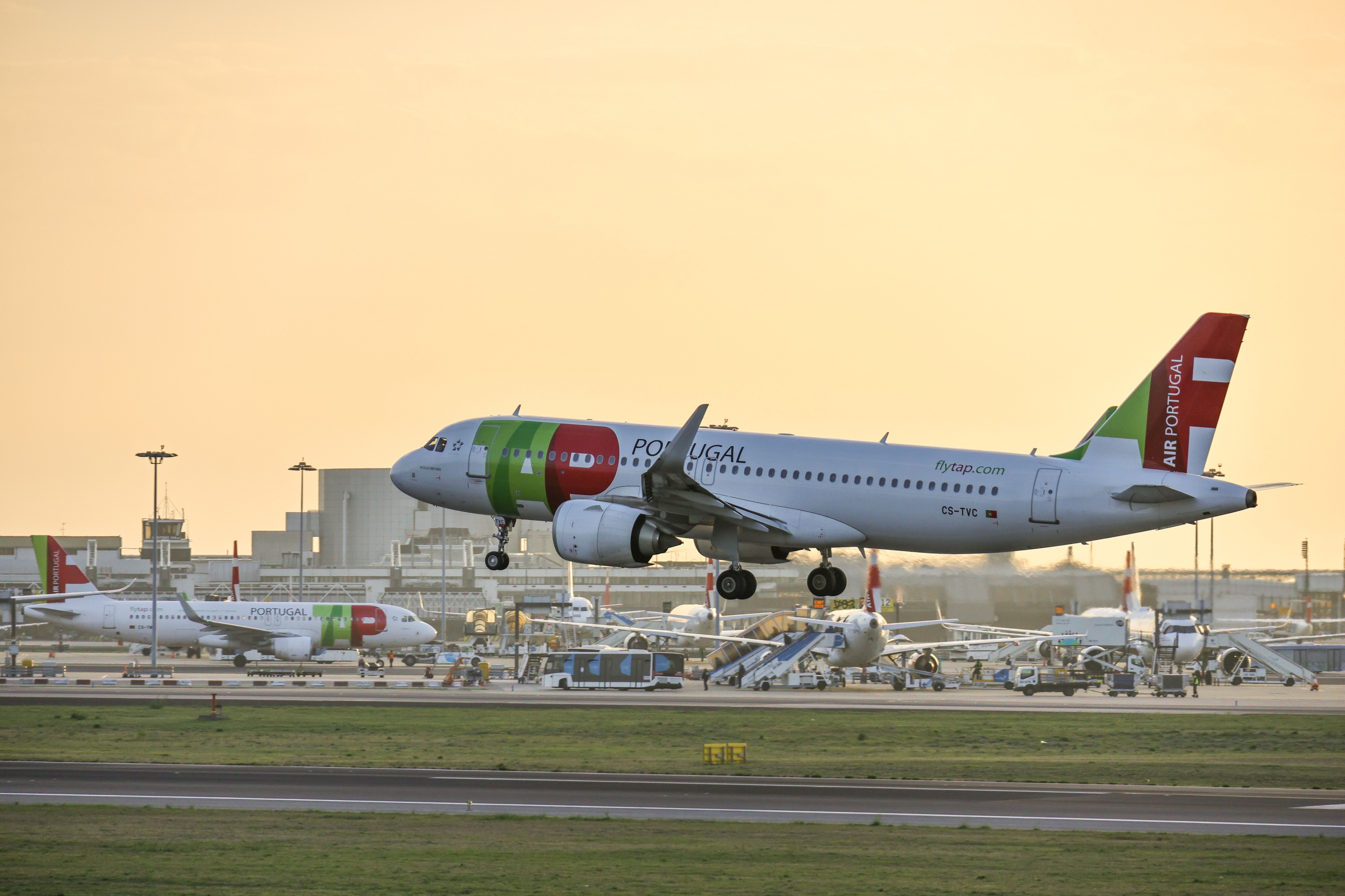 A side view of the TAP Air Portugal airplane departing from Humberto Delgado Airport at sunset