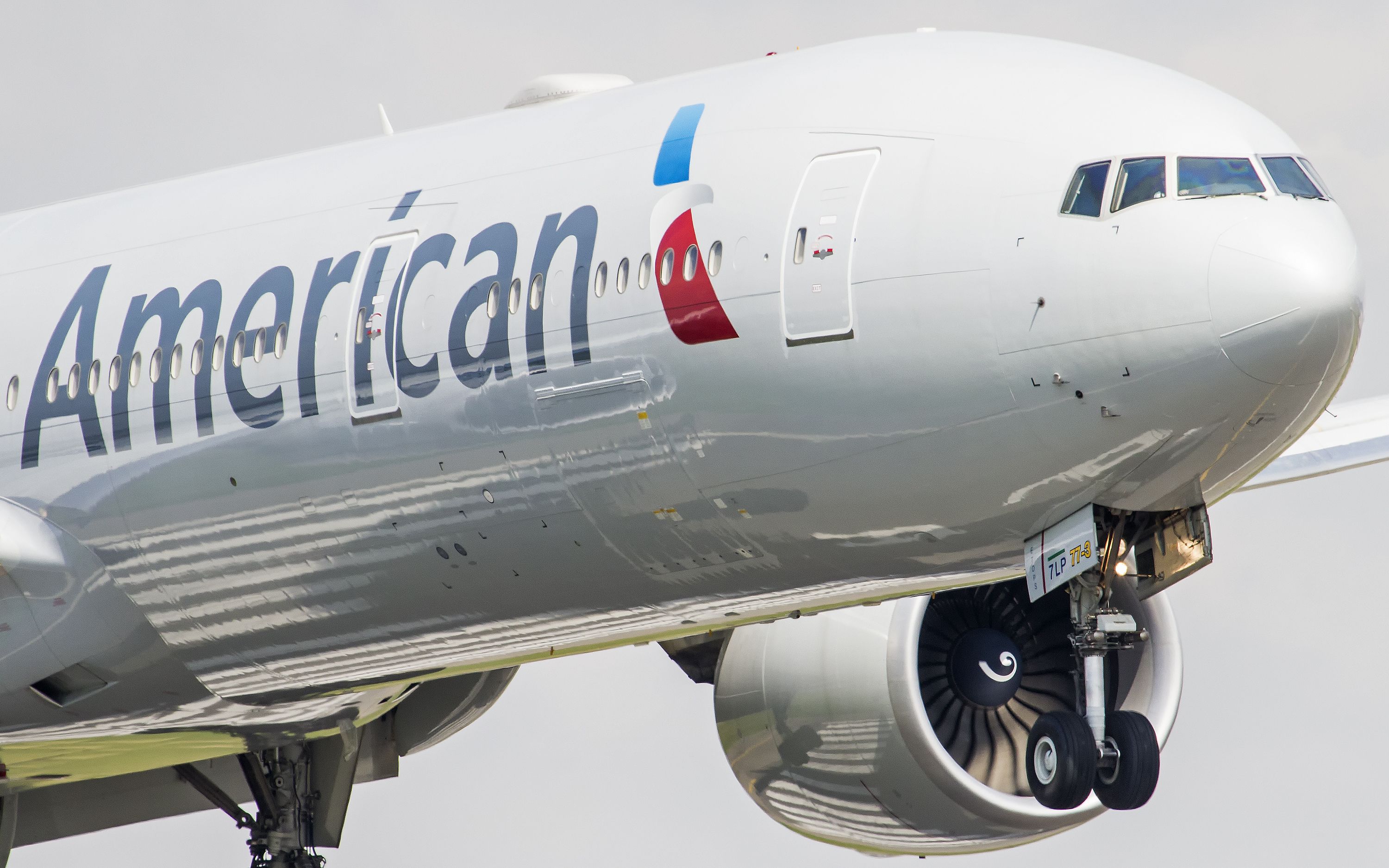 A closeup of an American Airlines Boeing 777-300ER flying in the sky.