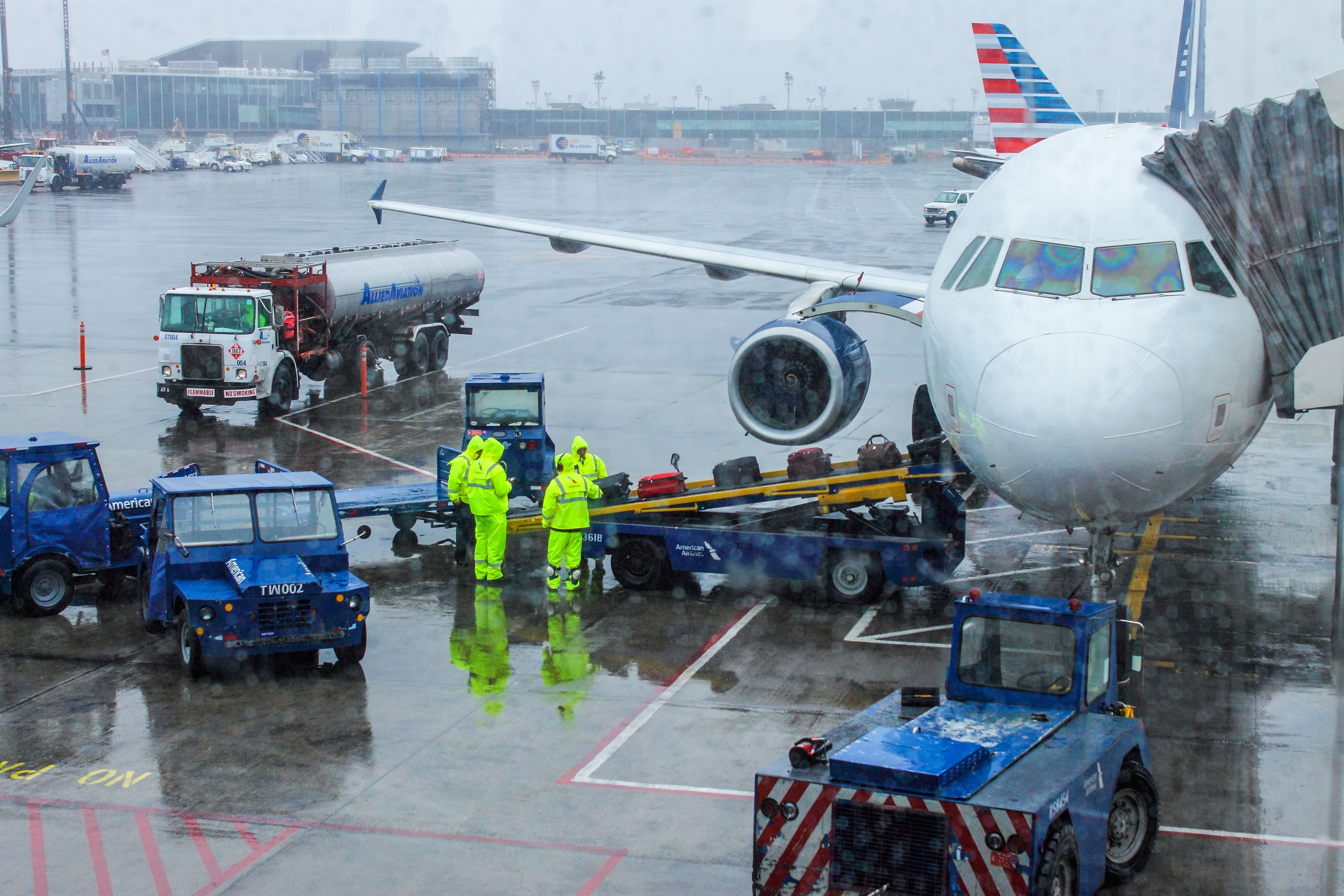 irport ground crew handling baggage on a rainy day at LaGuardia Airport preparing for flight.