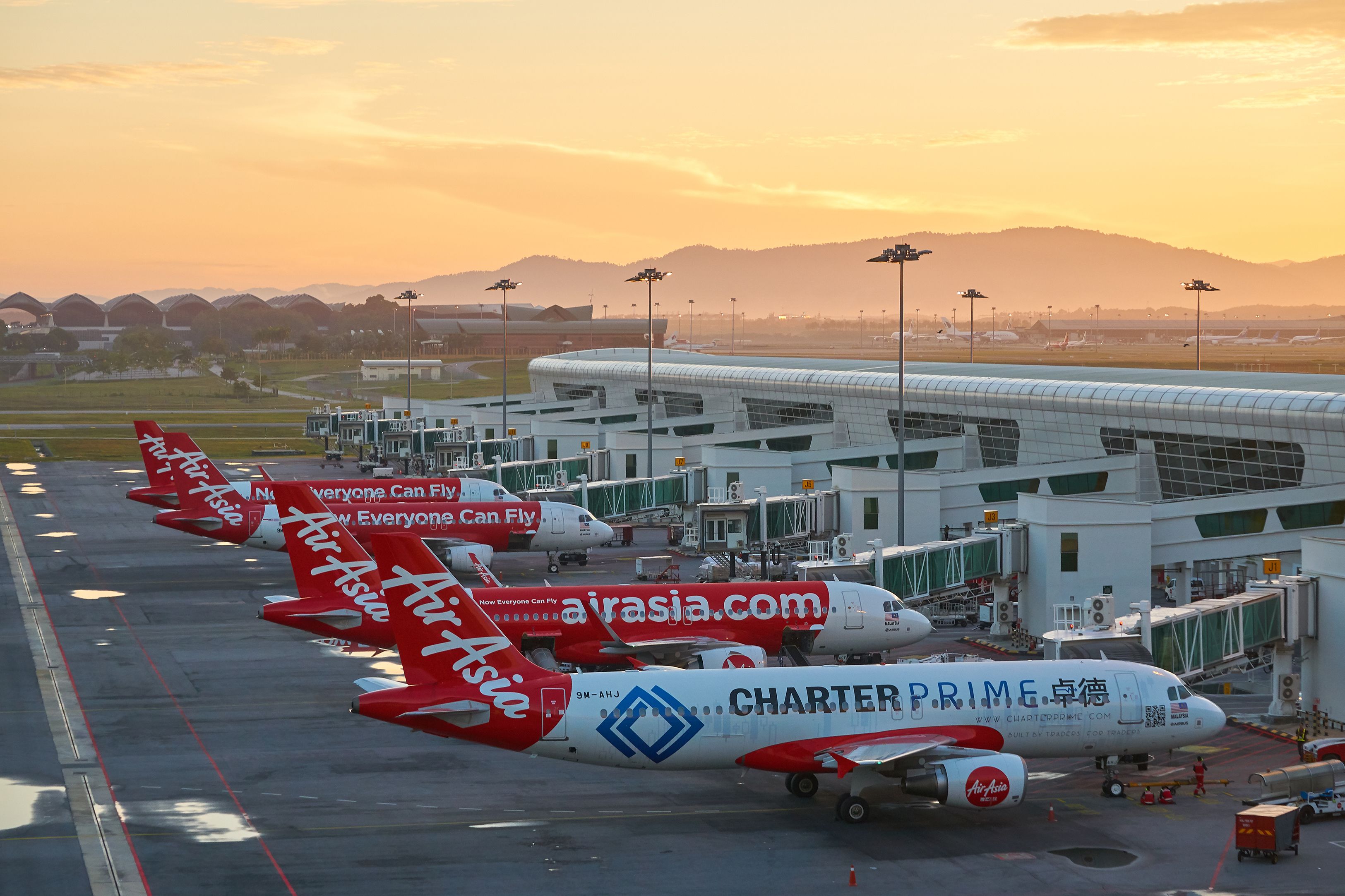 Several AirAsia aircraft parked at gates at Kuala Lumpur International Airport.