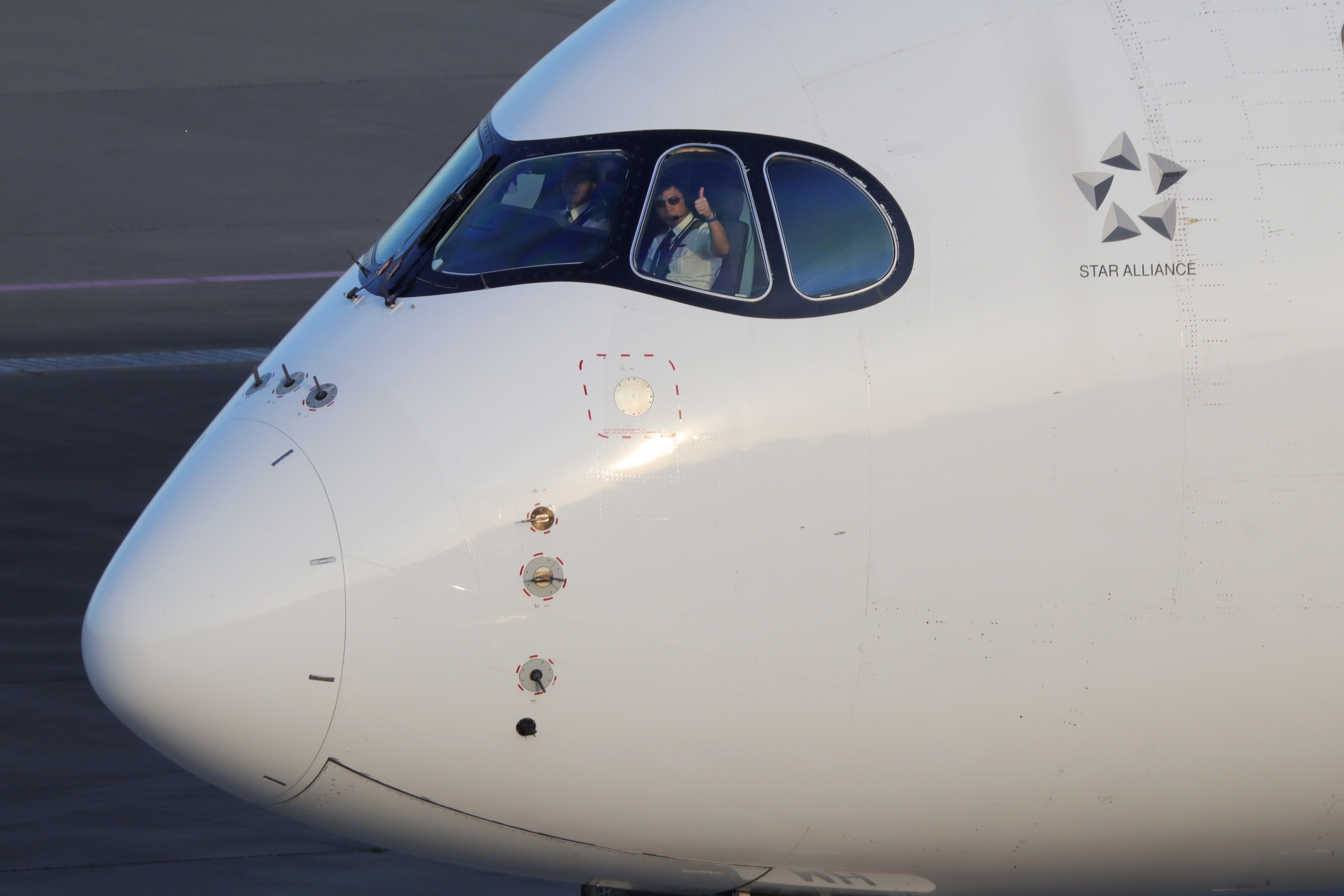 A closeup of the Singapore Airlines A350 flight deck, with a pilot giving a thumbs up.