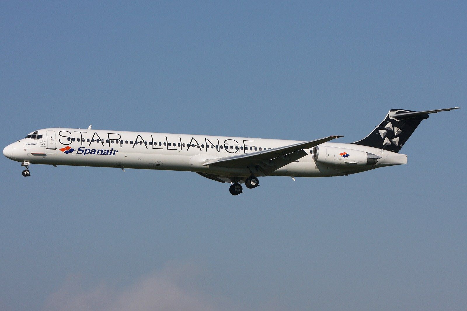 A Spanair MD 82 in Star Alliance livery flying in the sky.