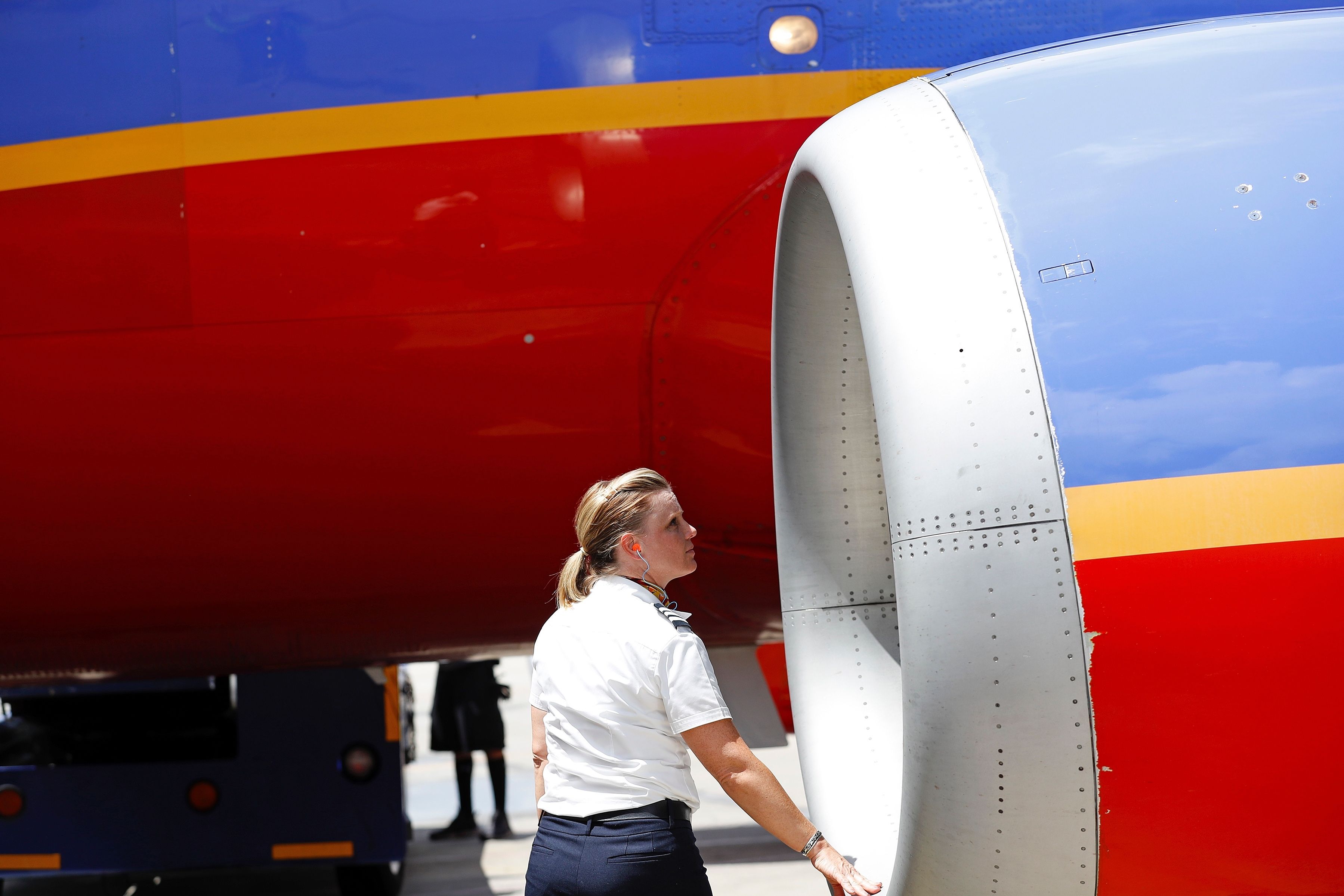 Woman in a flight crew uniform examines an engine on an aircraft with Southwest Airlines livery of red, yellow, and blue