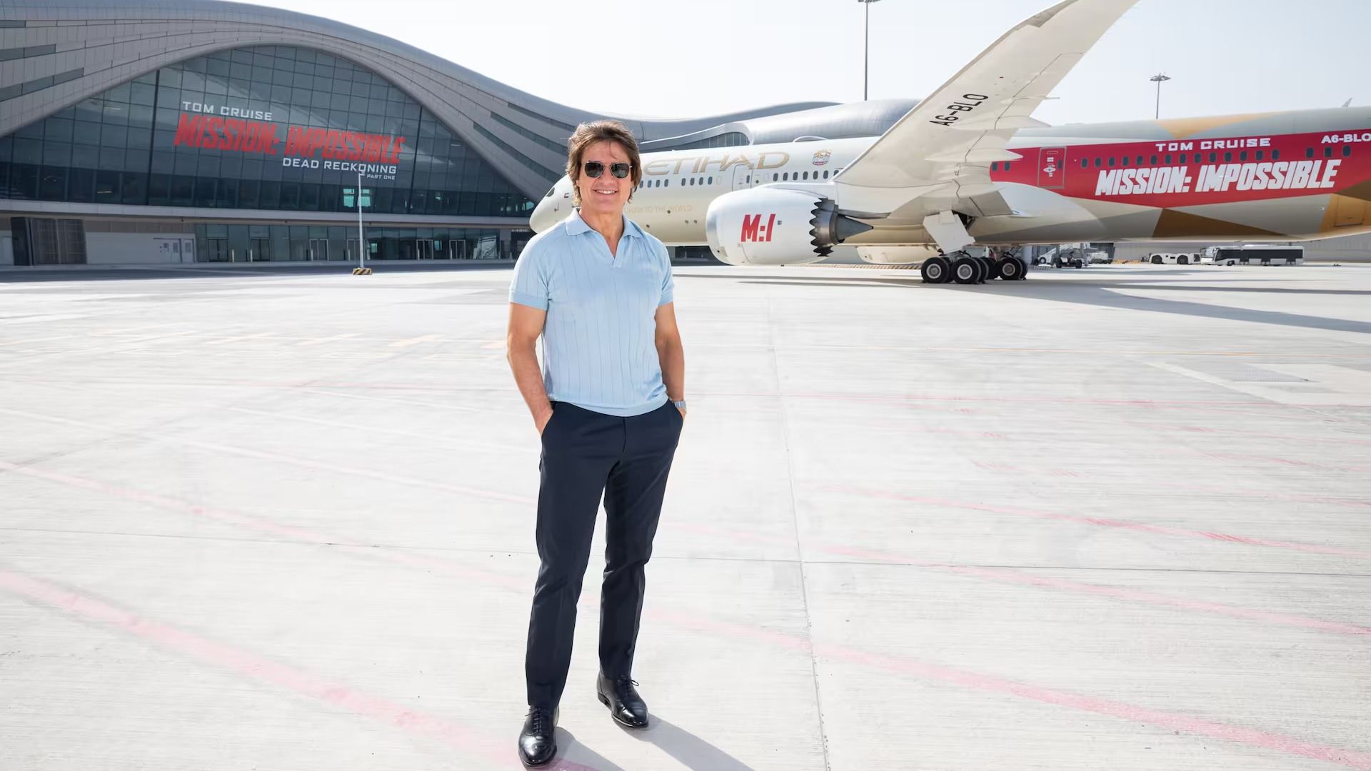 Tom Cruise in front of an Etihad Airways aircraft and Abu Dhabi Airport.
