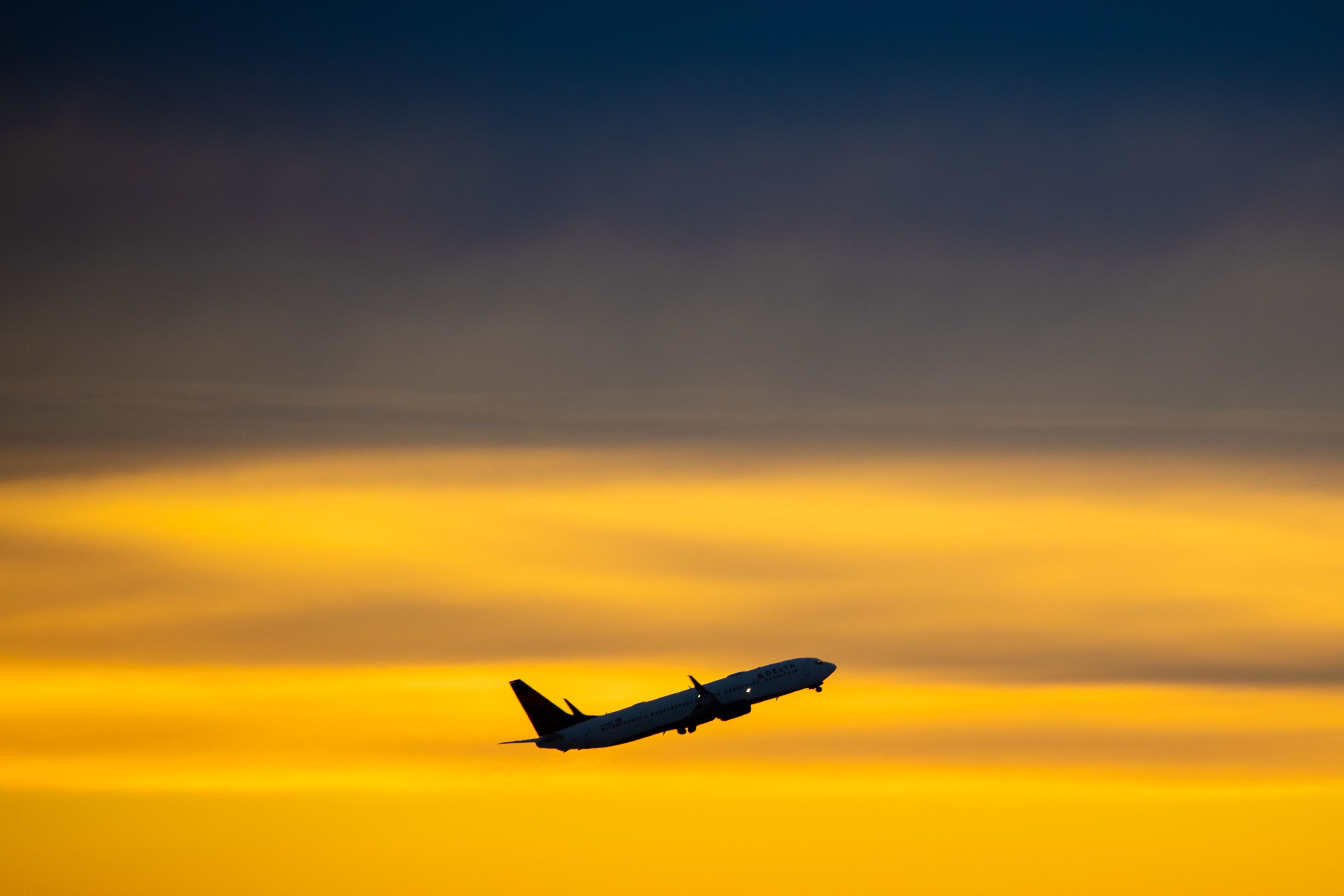 A Delta Air Lines plane against the sunrise in the sky.