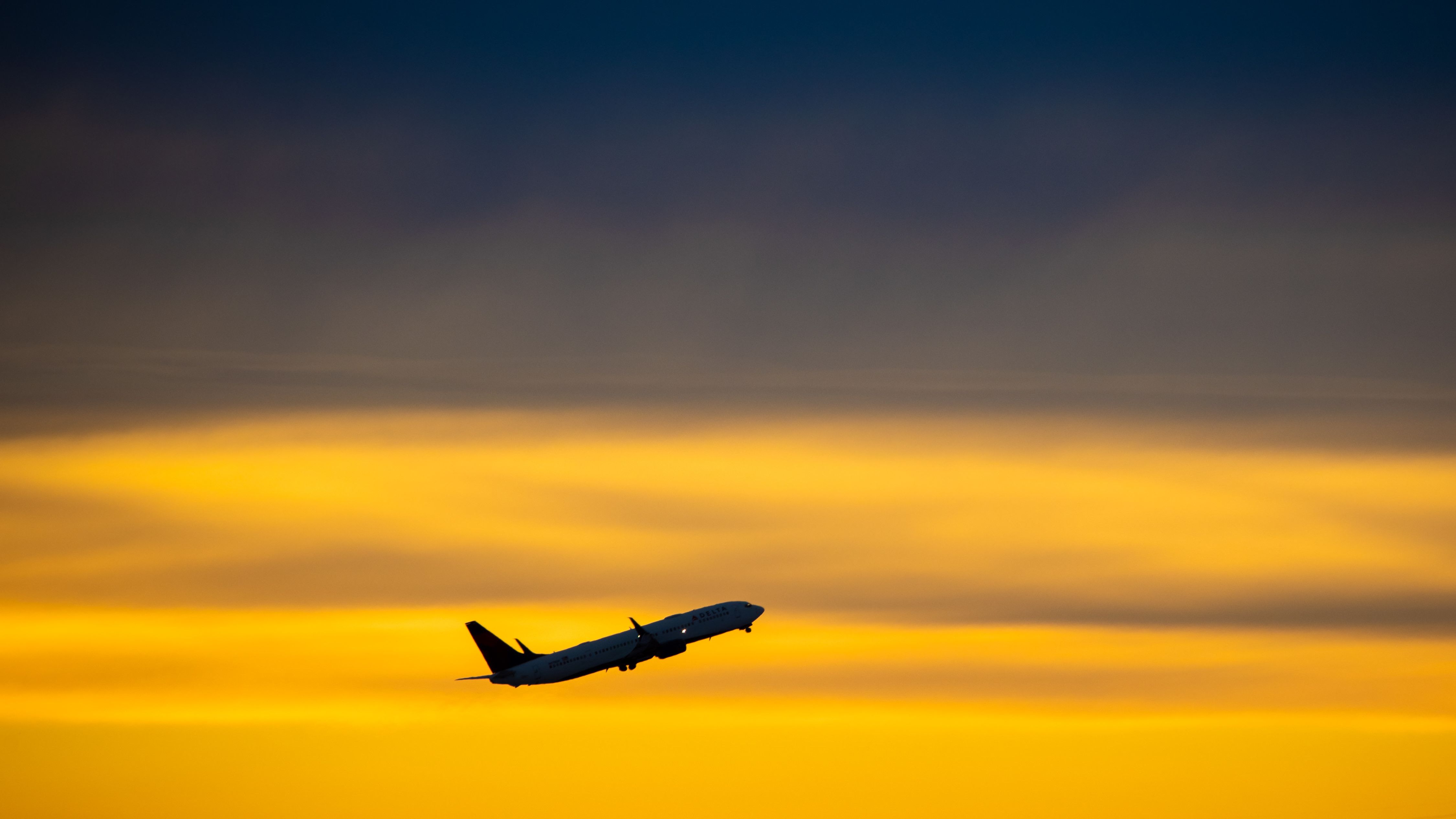 A Delta Air Lines plane against the sunrise in the sky.