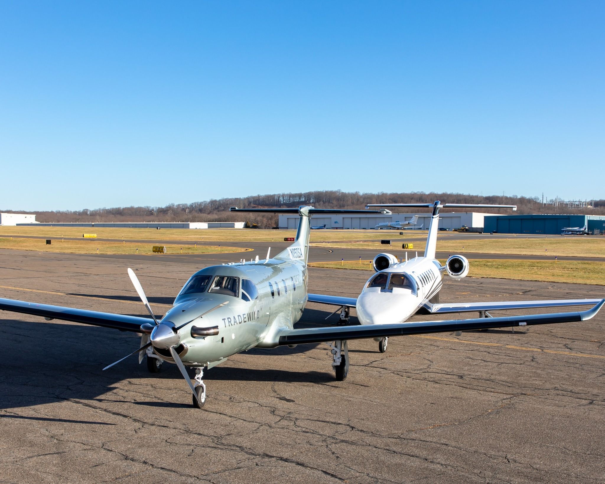 A Tradewind Aviation jet aircraft and turboprop parked side by side at an airport.