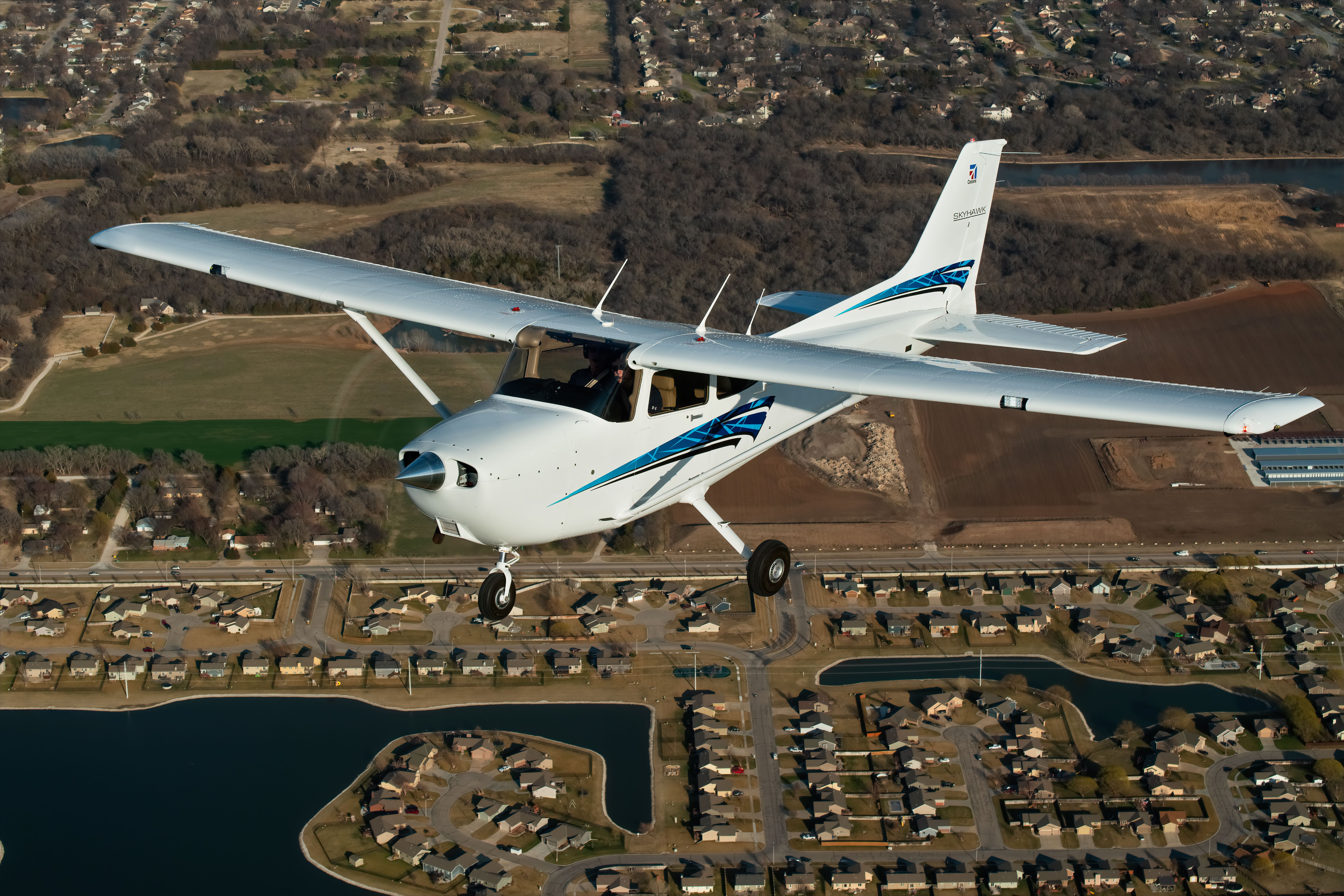 A Cessna Skyhawk flying over an urban area.