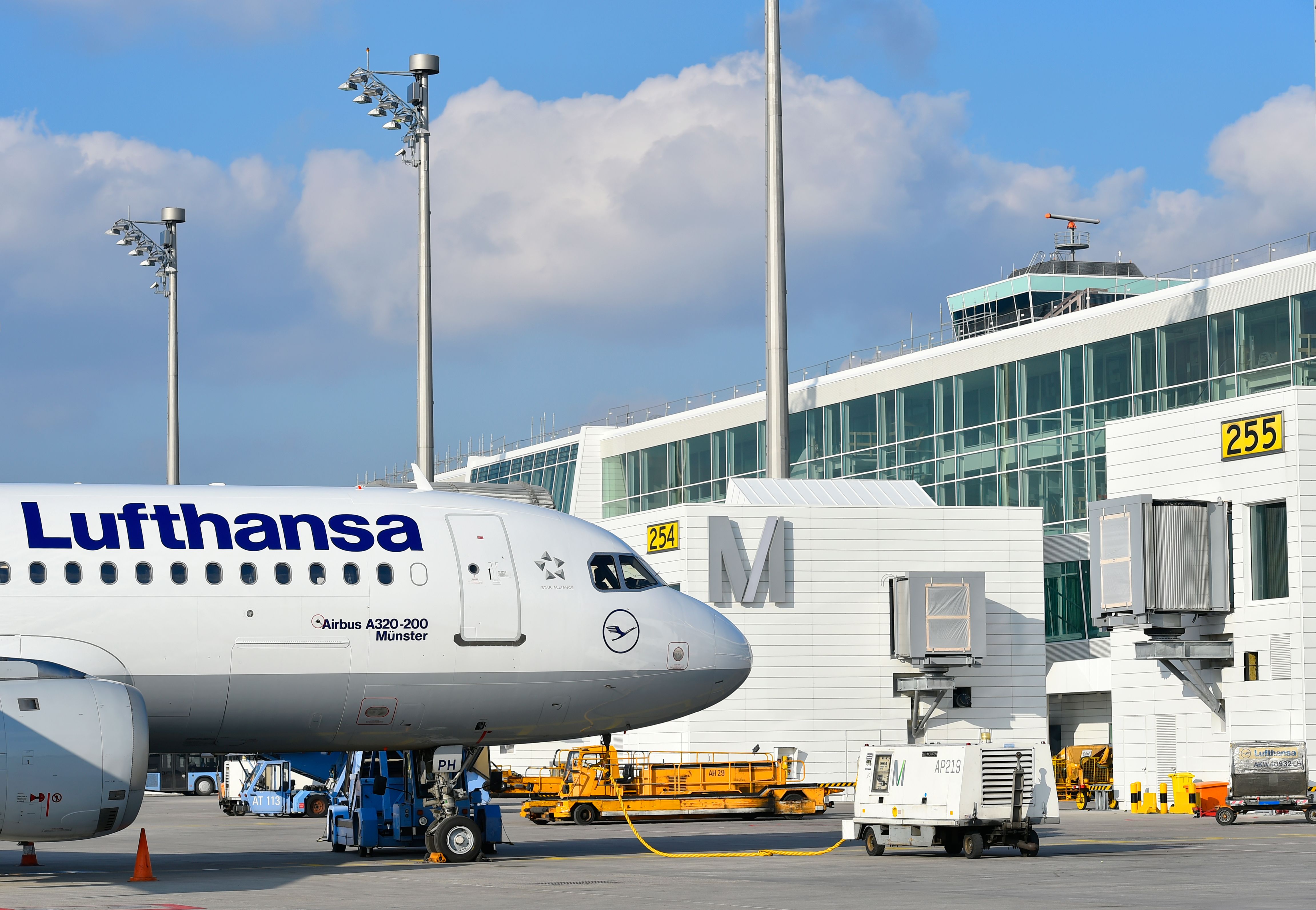 A Lufthansa Airbus A320 Parked At a gate at Munich Airport In Sunny Conditions.