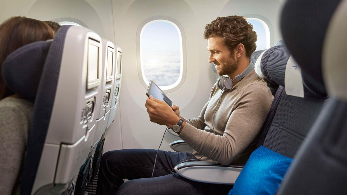 A passenger using a tablet in British Airways' World Traveler economy cabin.