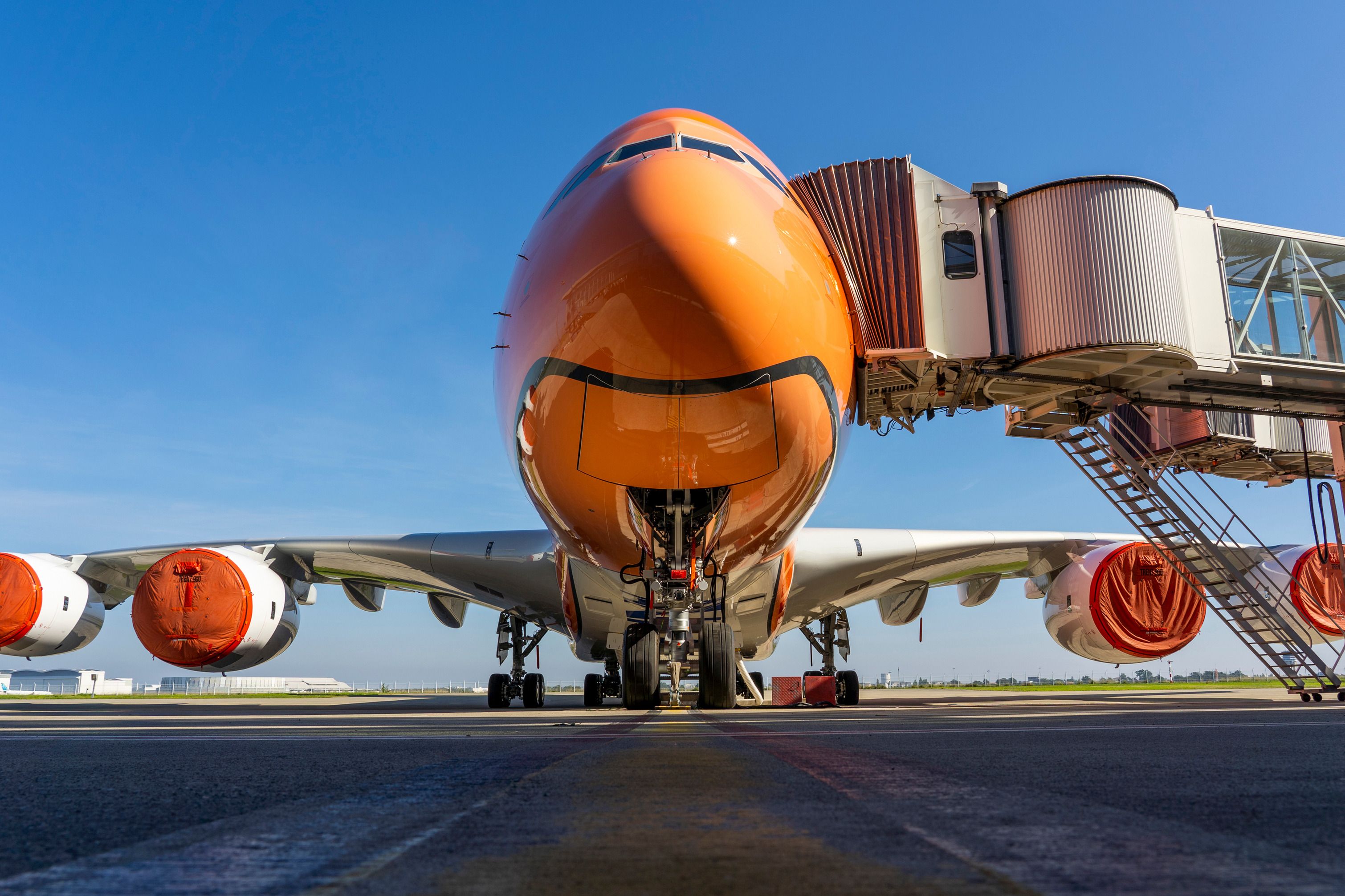 An orange All Nippon Airways Airbus A380 parked at an airport gate.