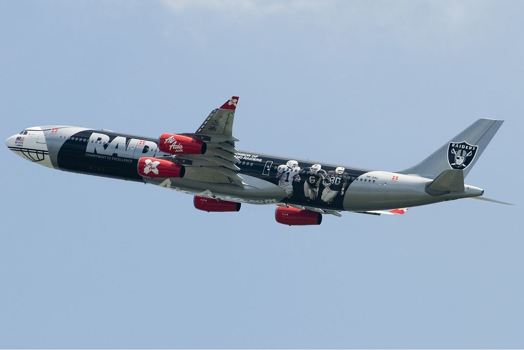 An AirAsia X Airbus A340-300 in Oakland Raiders livery flying overhead.