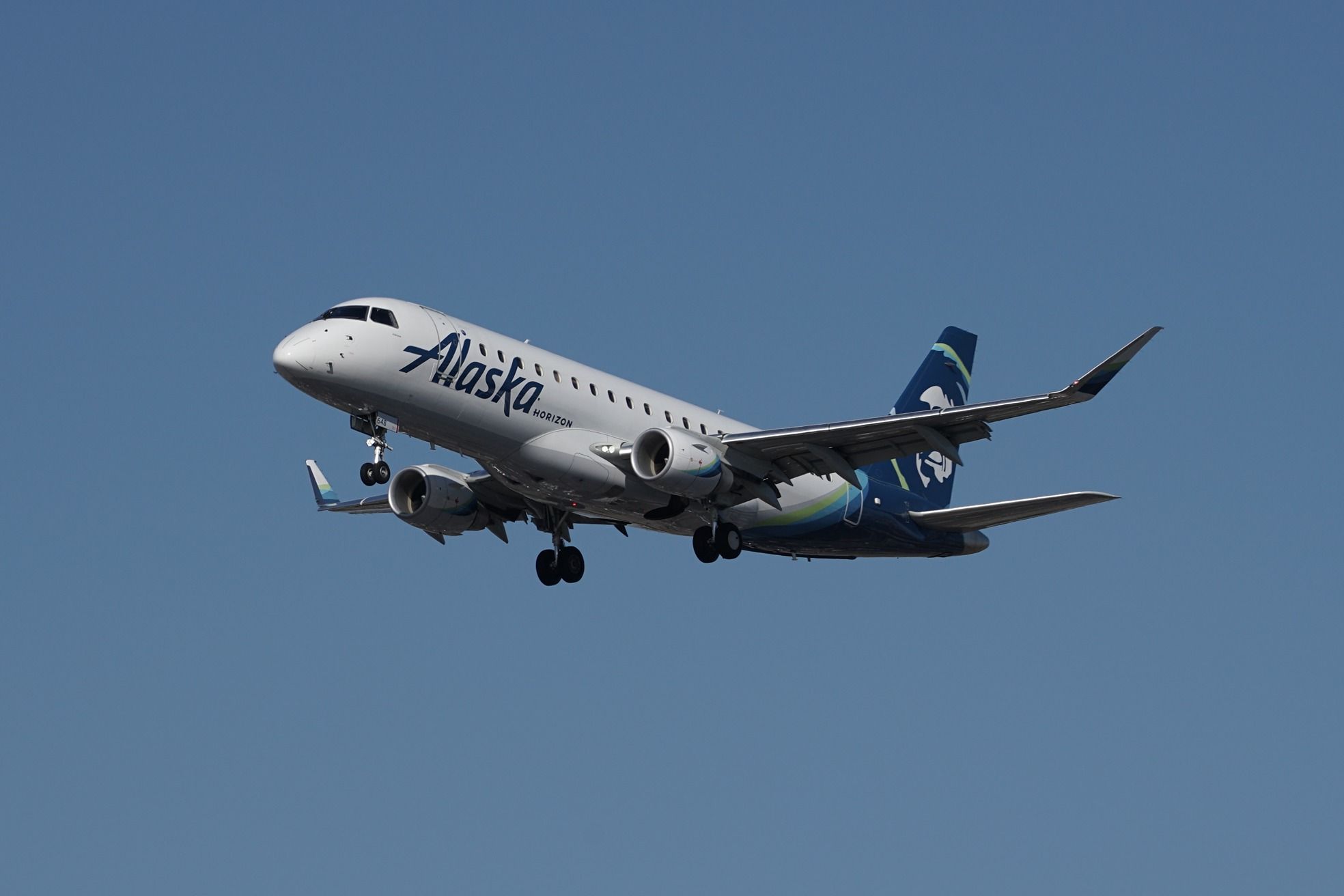 A Horizon Air Embraer E175 flies in the sky.