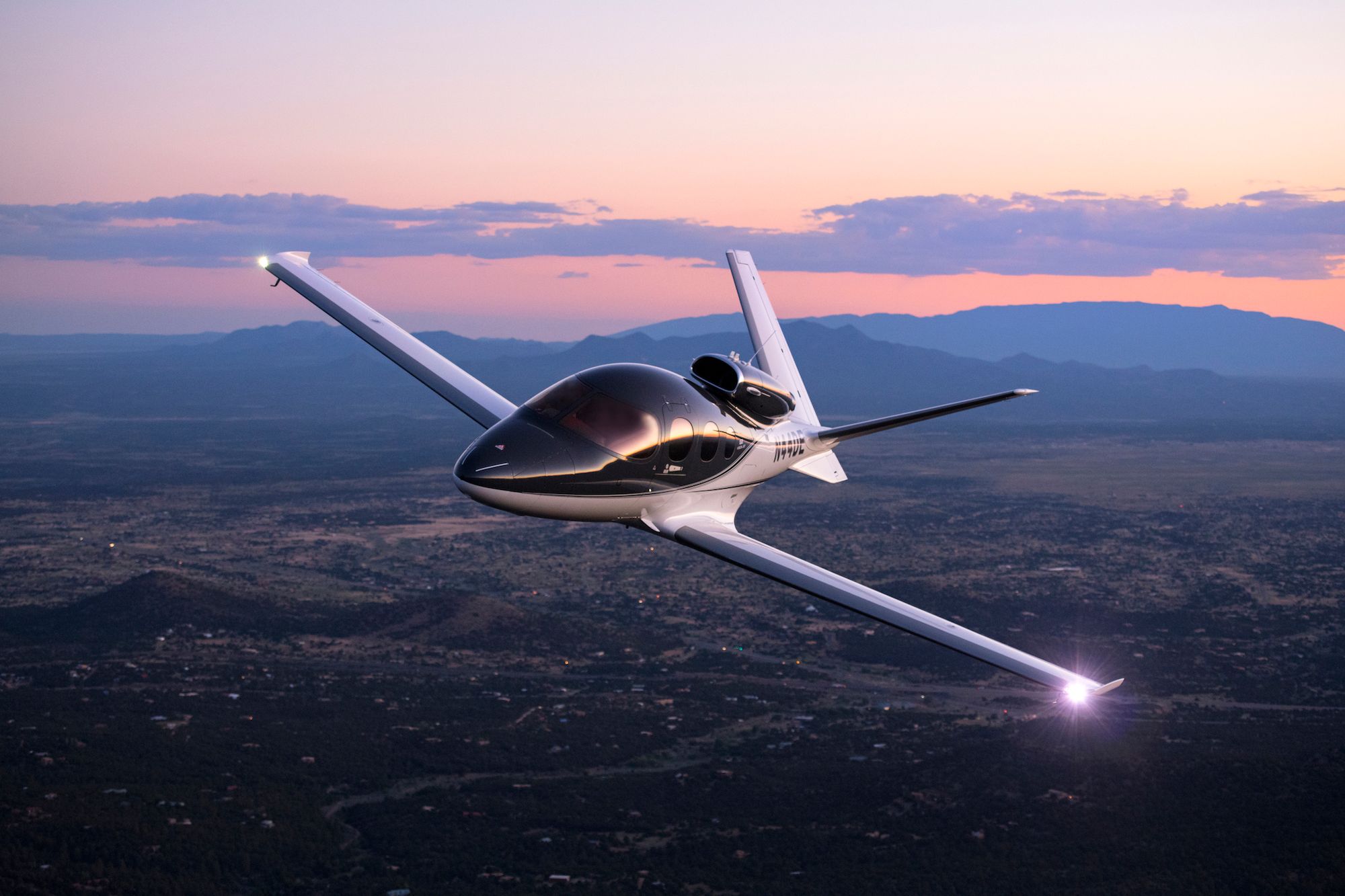 A Cirrus SF50 Vision Jet flying over a city.