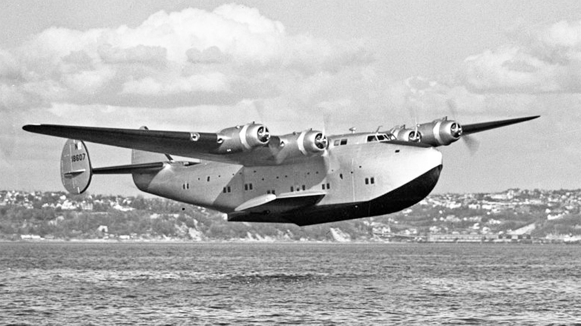 A Boeing 314 flying just above water.
