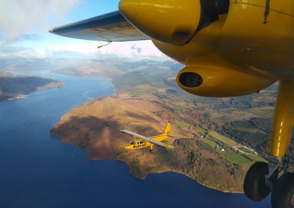 A Hebridean Air Services aircraft flying over water.