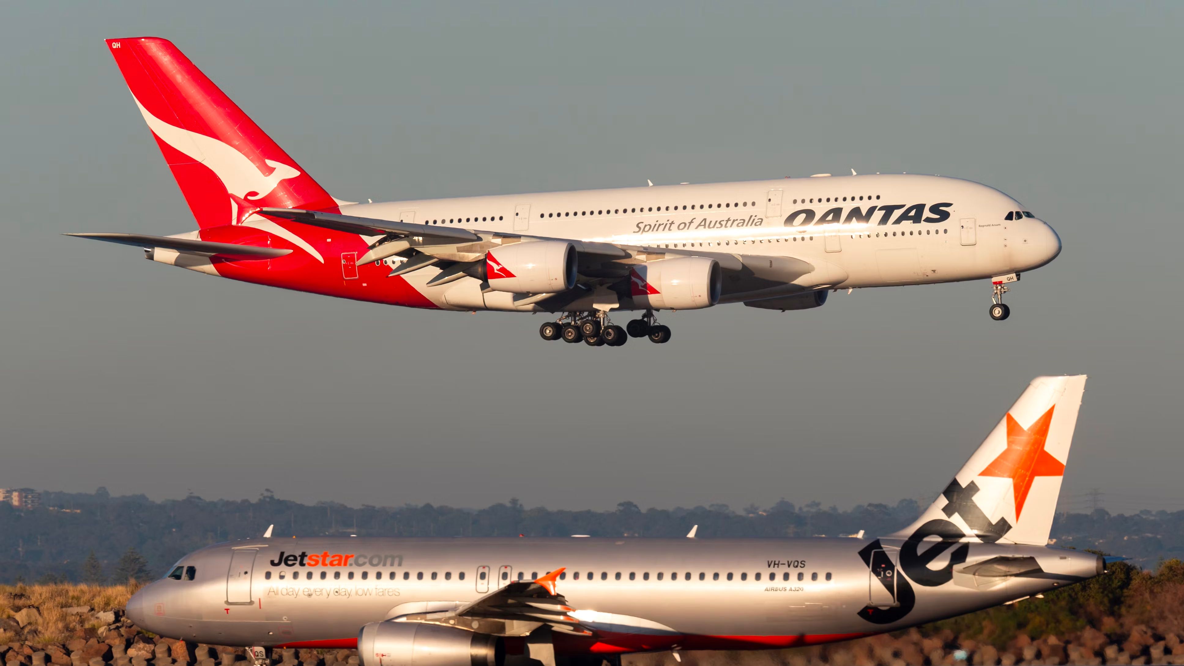 A Qantas Airbus A380 about to land as a Jetstar Airbus A320 waits on a taxiway.