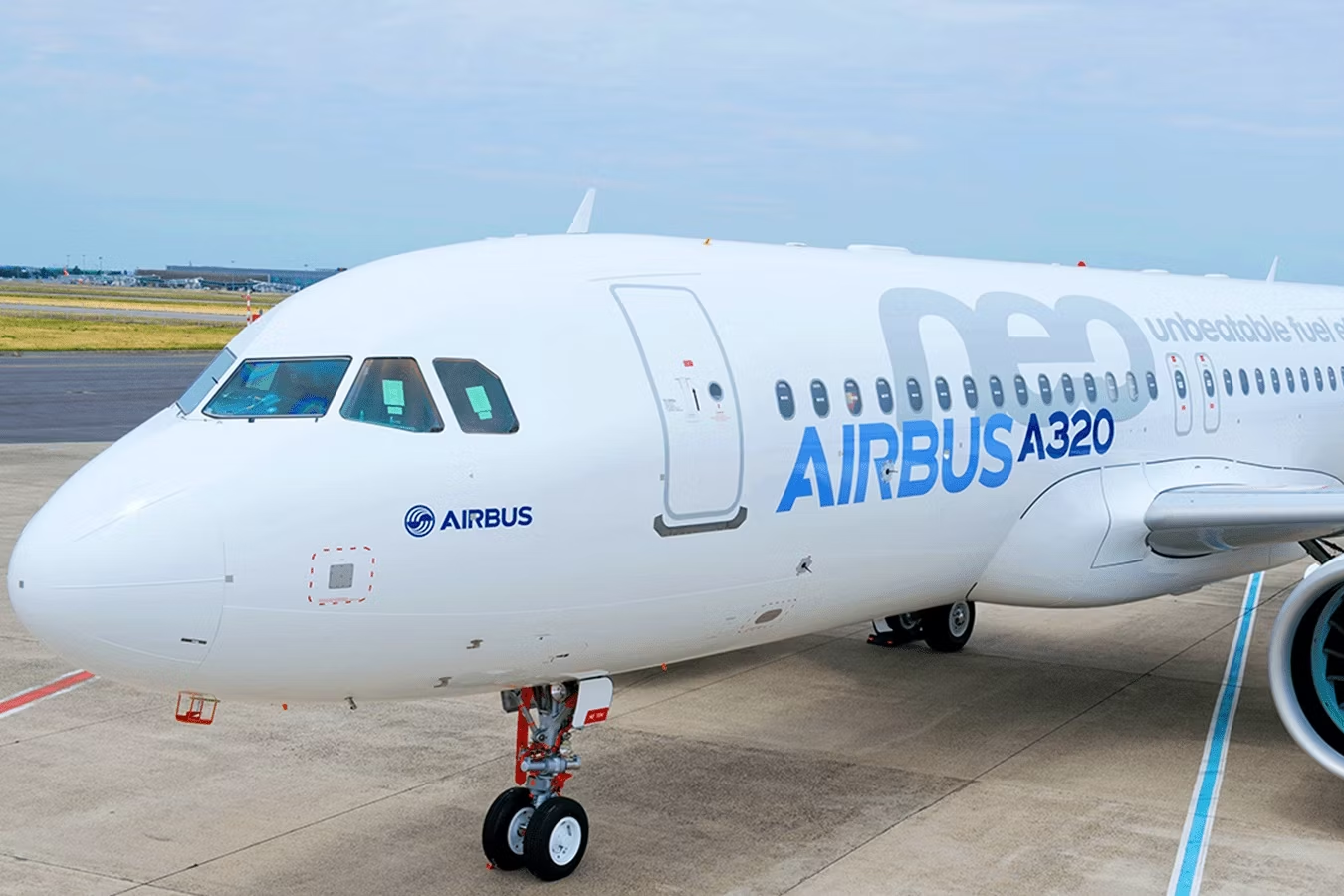 An Airbus A320neo in house livery parked at an airport.
