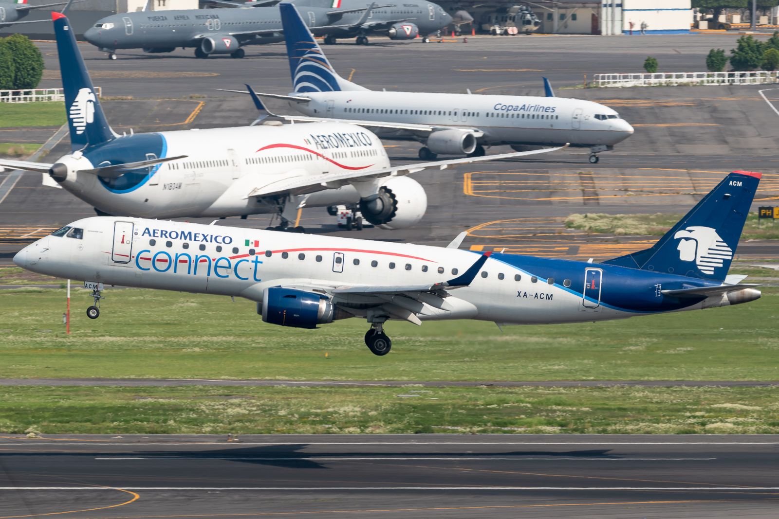 An Aeroméxico Connect Embraer ERJ-190-100LR flying in front of Aeroméxico and CopaAirlines aircraft.