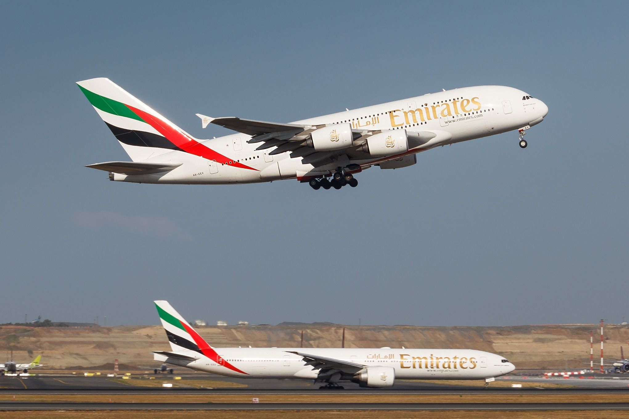 An Emirates Airbus A380 taking off as an Emirates Boeing 777 taxis.