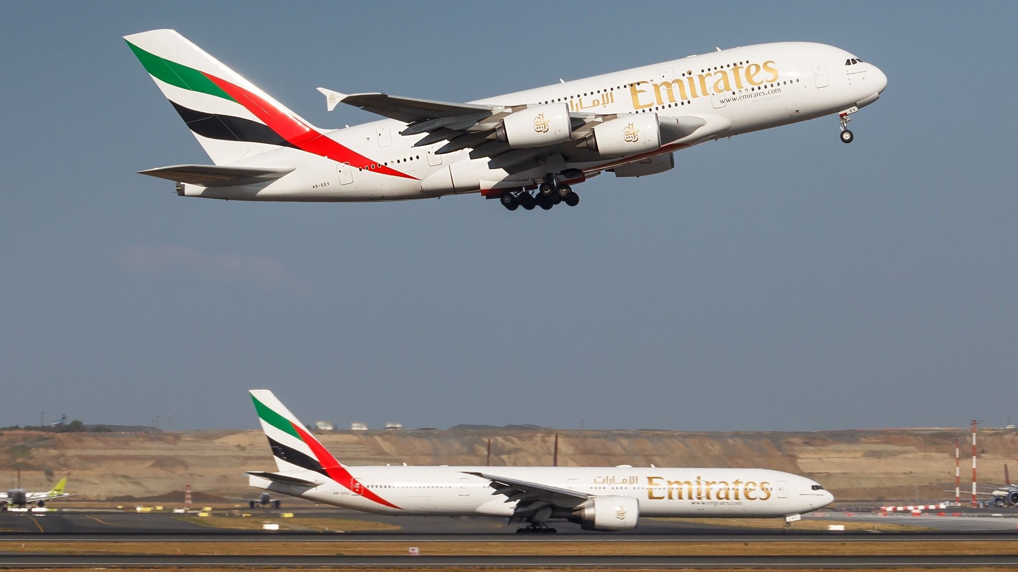 An Emirates Airbus A380 taking off as an Emirates Boeing 777 taxis.