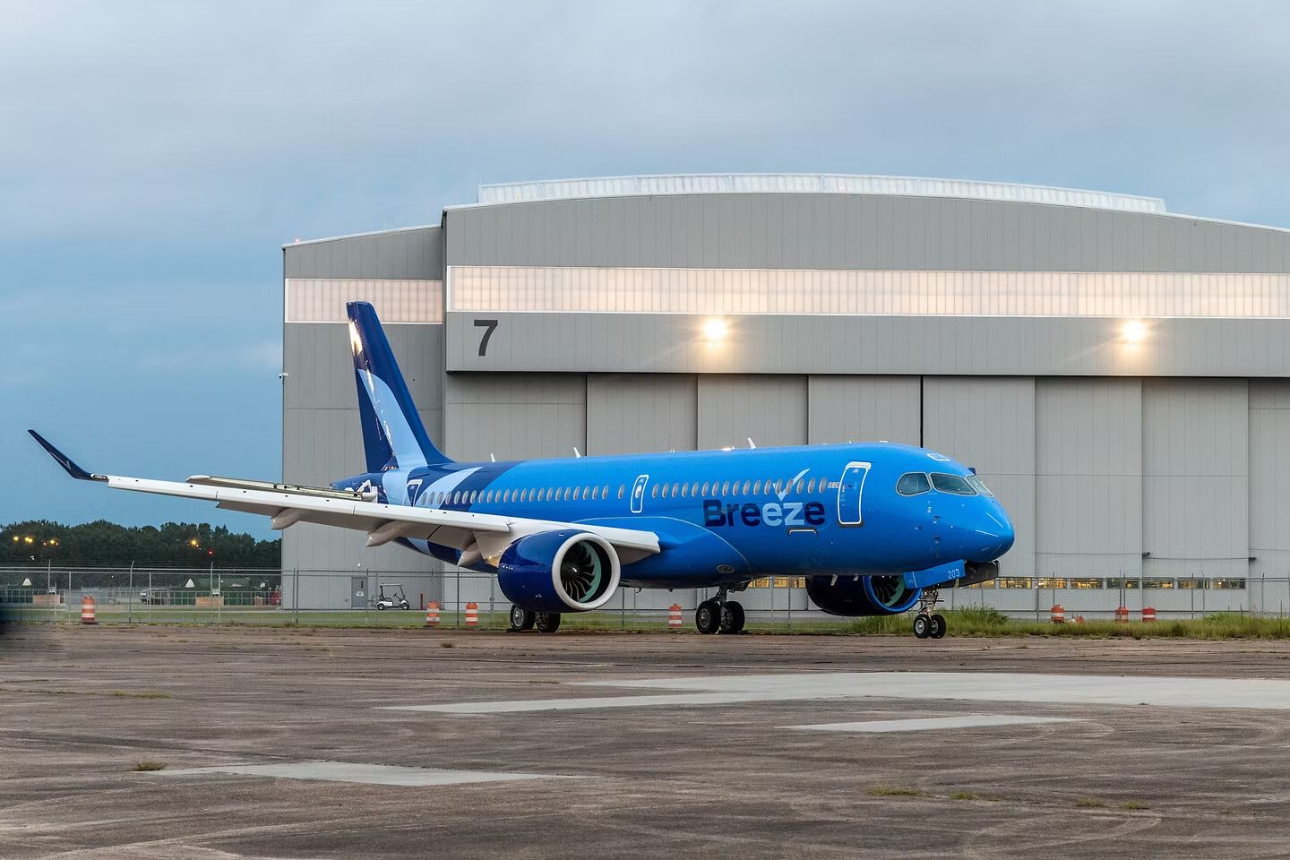A Breeze Airways Airbus A220 parked at an airfield.