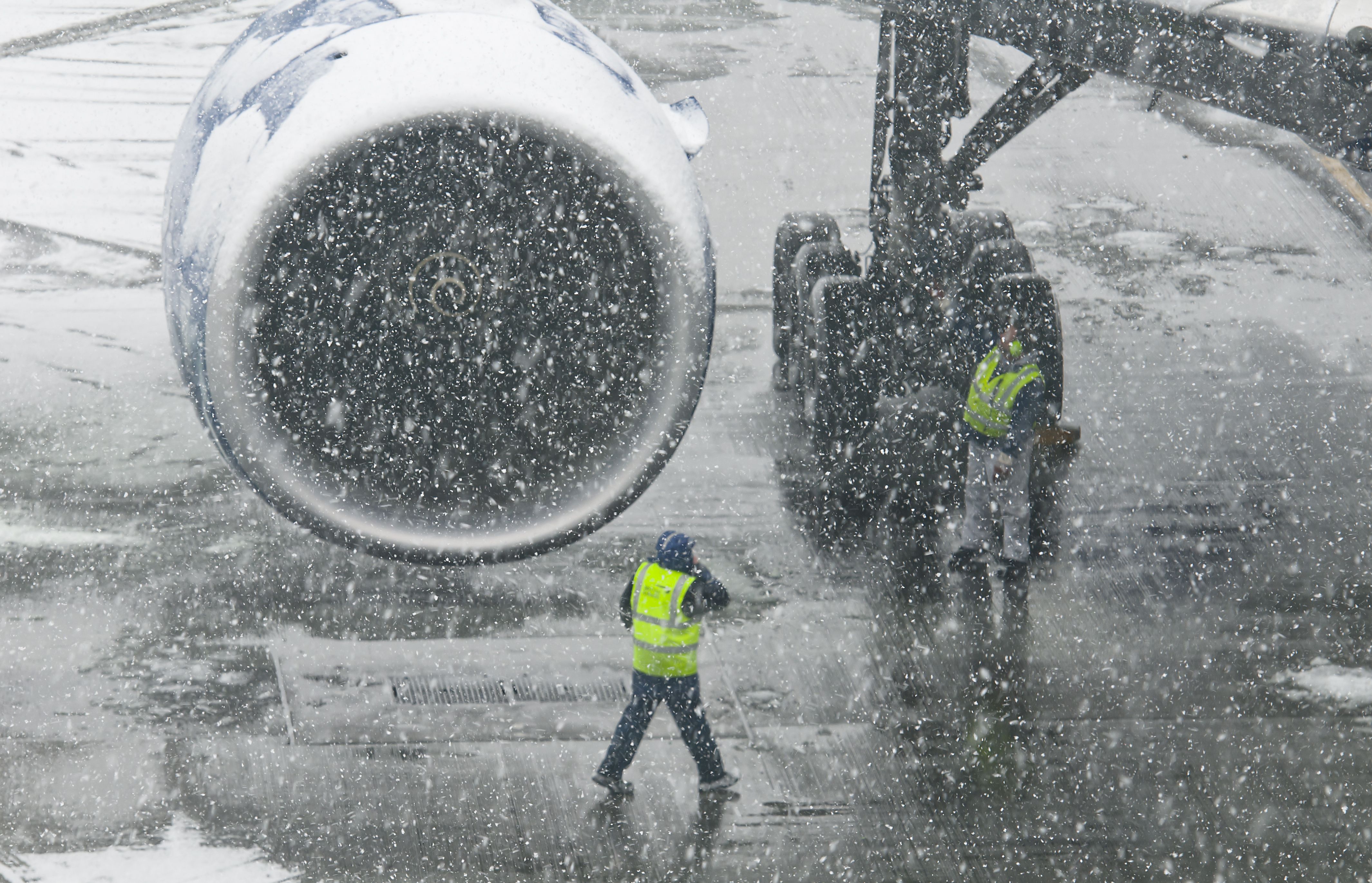 Ground handlers attending an aircraft during a snow storm.