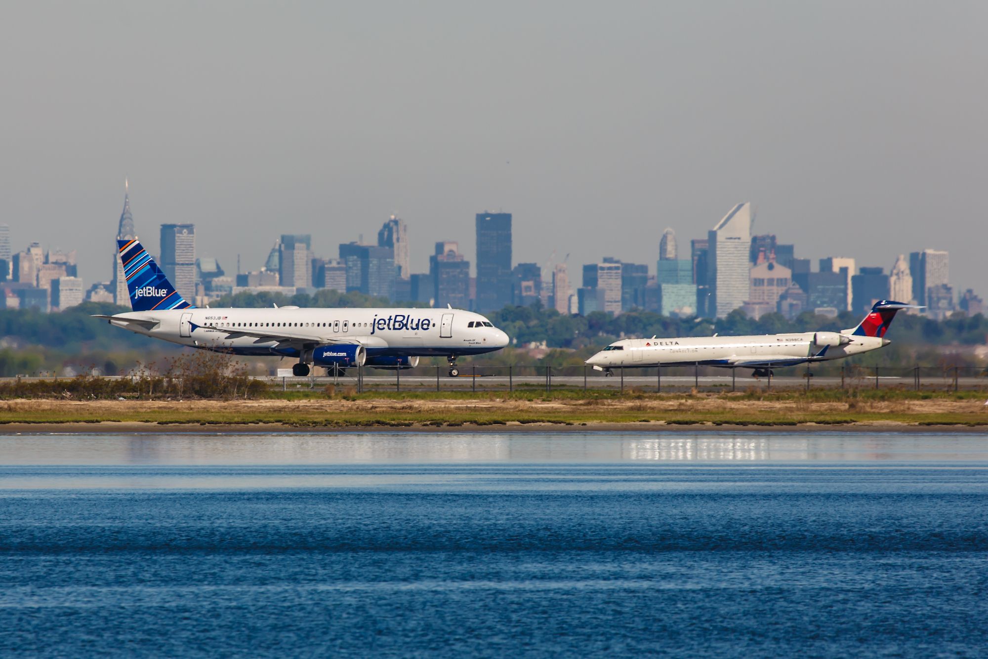A JetBlue Airbus A320 and Delta Air Lines Mitsubishi CRJ at New York John F Kennedy International Airport.