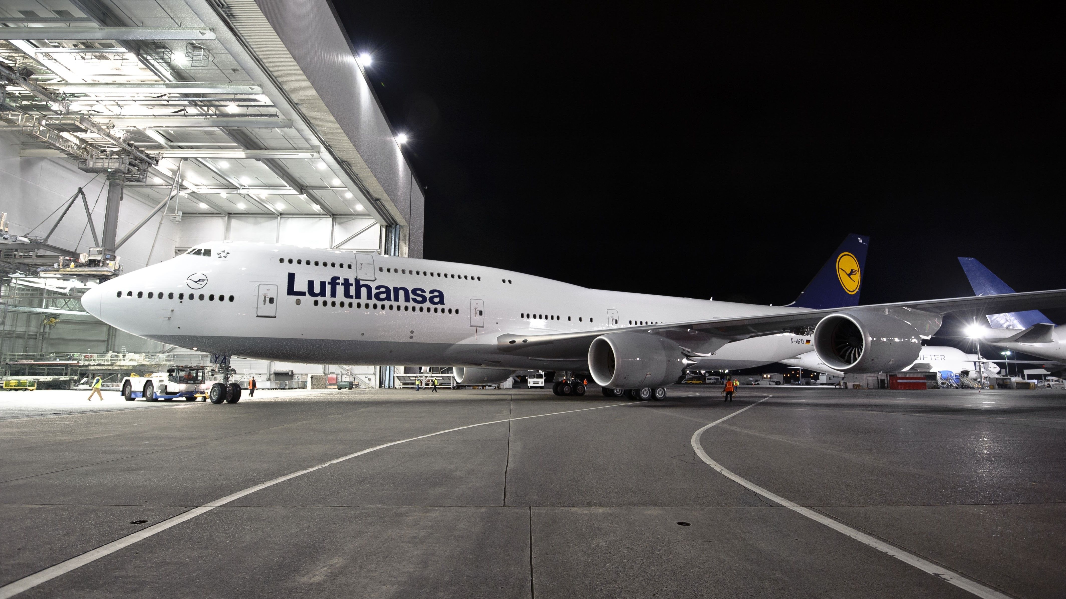 A Lufthansa Boeing 747-8 Being Pushed Out Of A Hangar At Night.