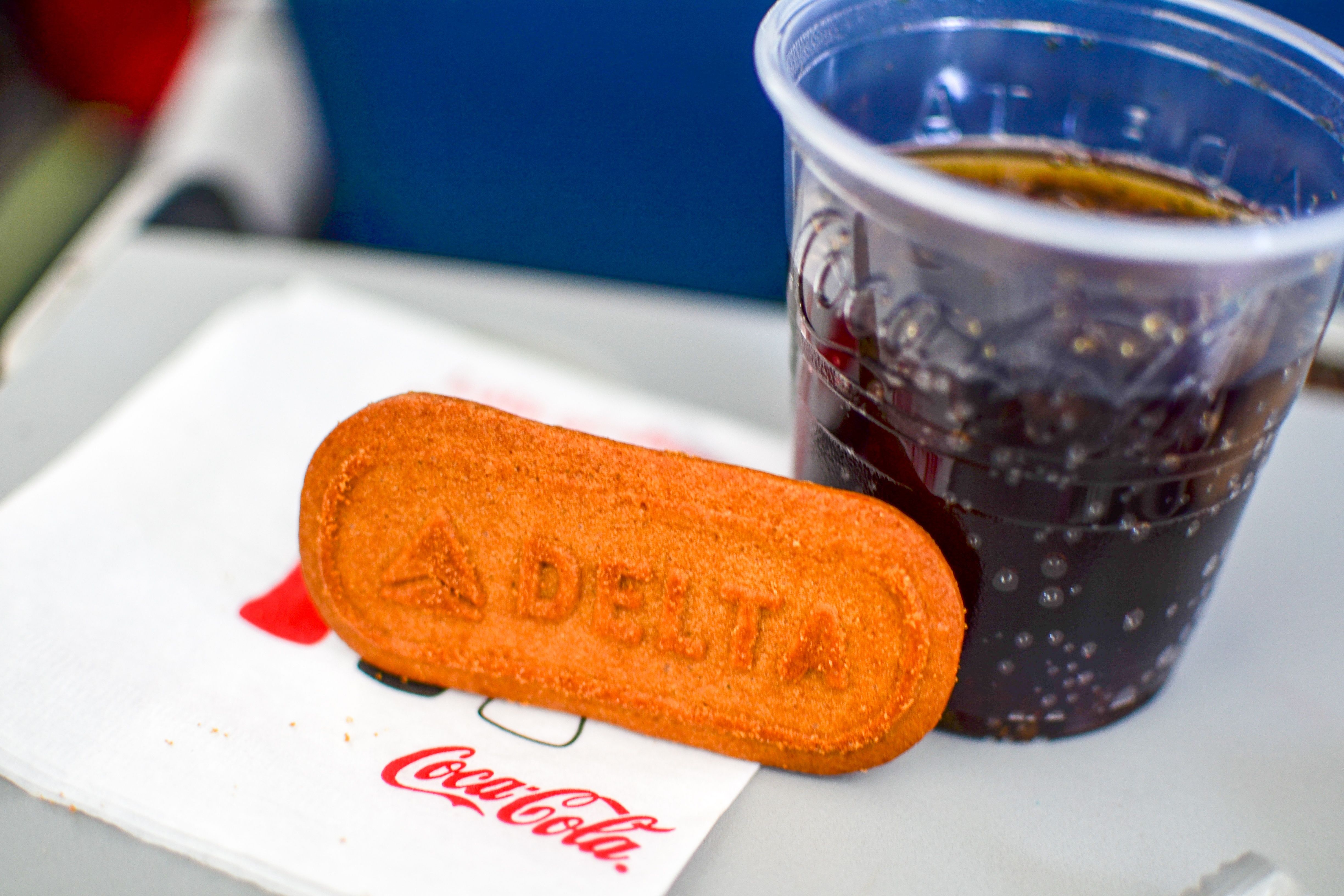 A Biscoff cookie with Delta Air Lines' logo on it, next to a coke.