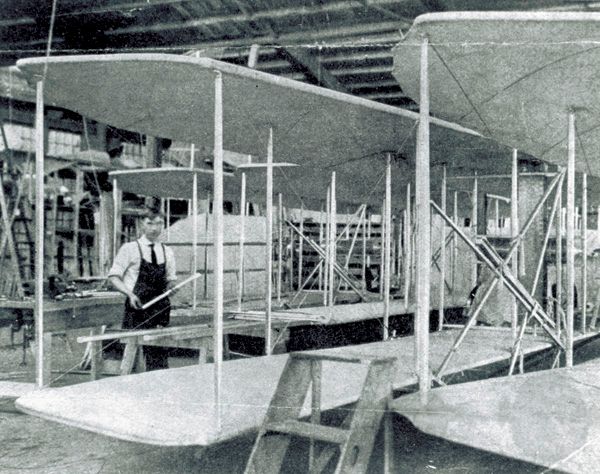 Print of a newspaper photograph showing mechanic Albert M. Flora at work assembling wings in the Wright Company factory.