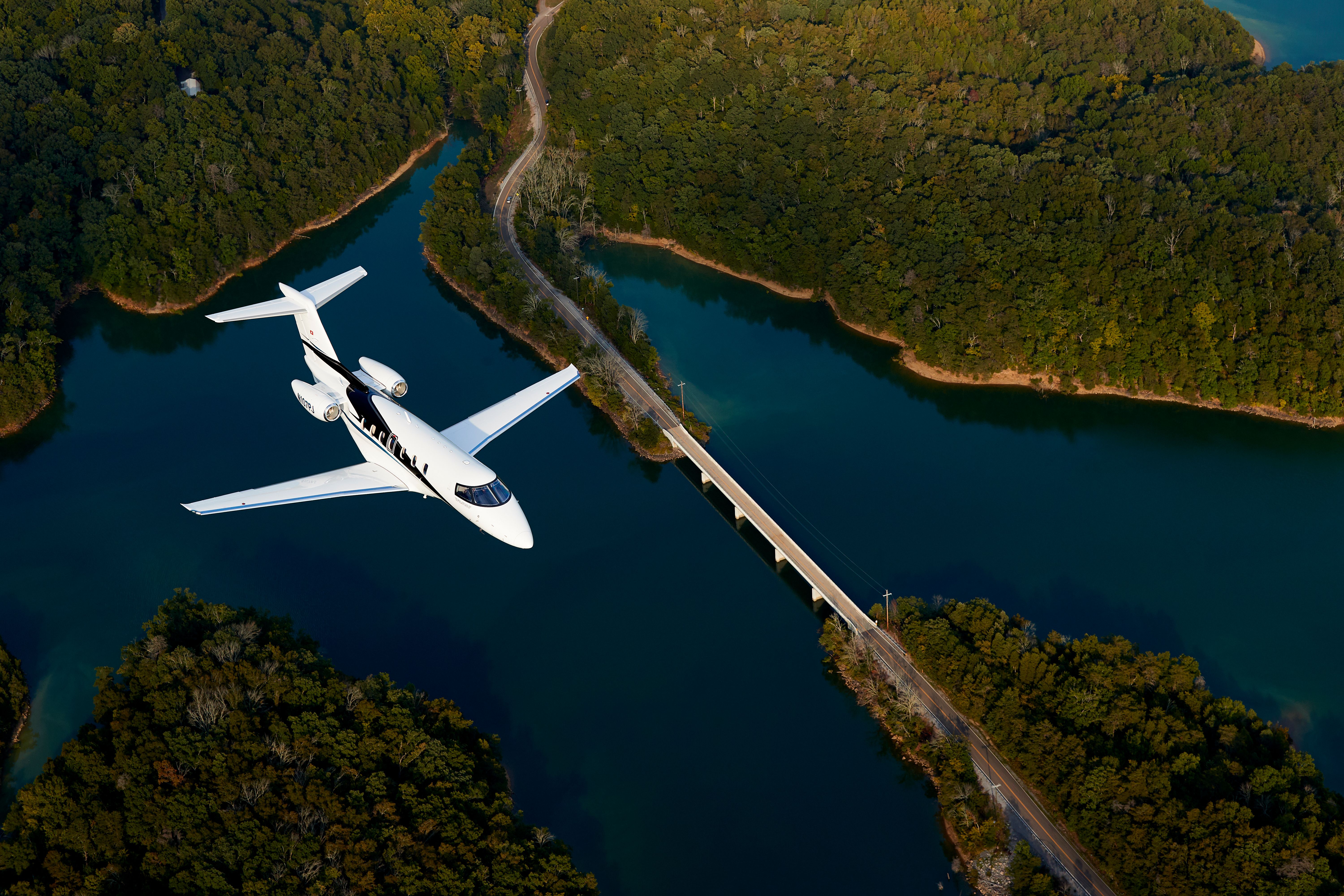 The Pilatus PC-24 Super Versatile Jet flying over water.