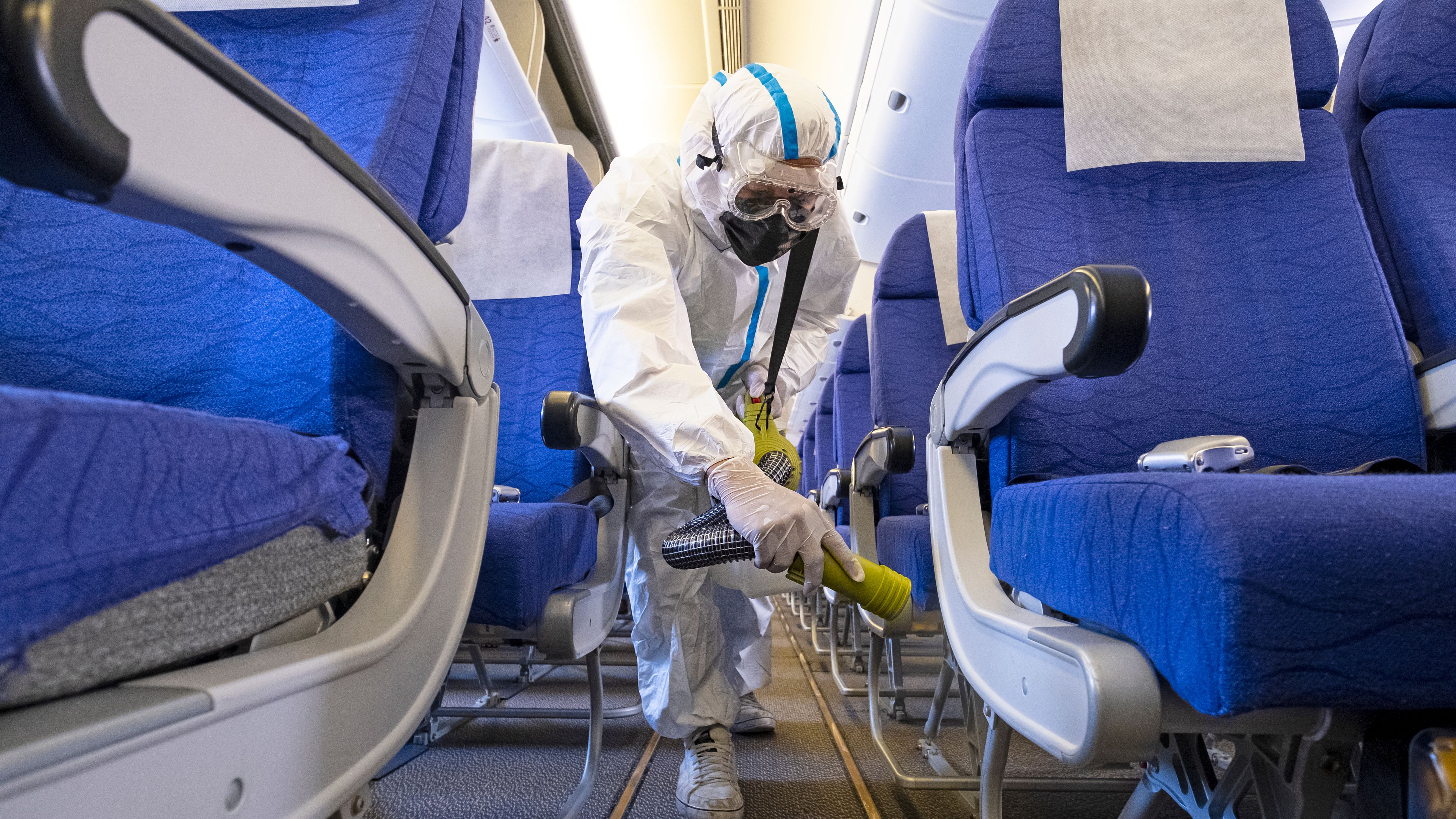 An individual in full PPE cleaning an aircraft cabin.