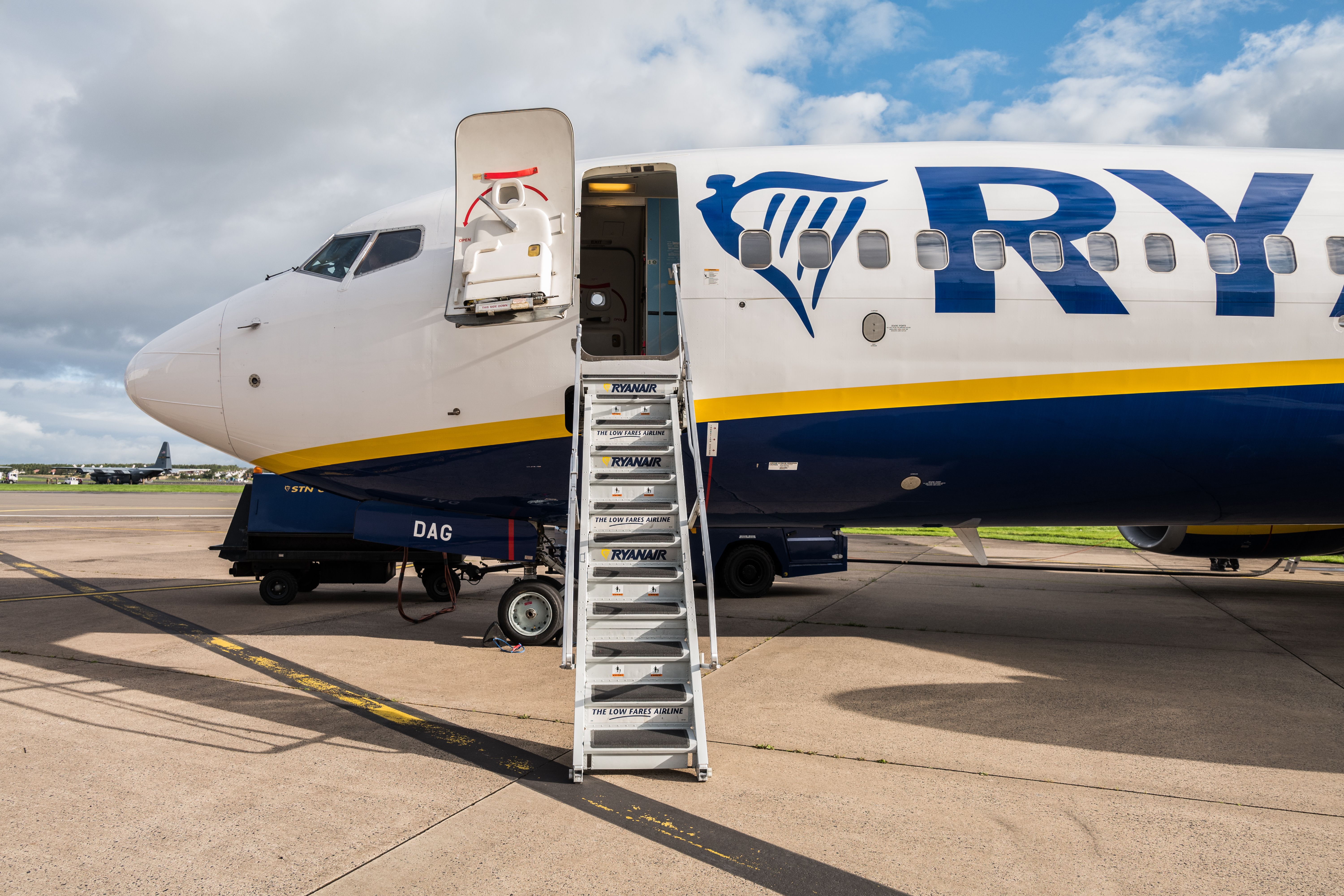 A Ryanair aircraft parked at an airport with its main door stairs down.