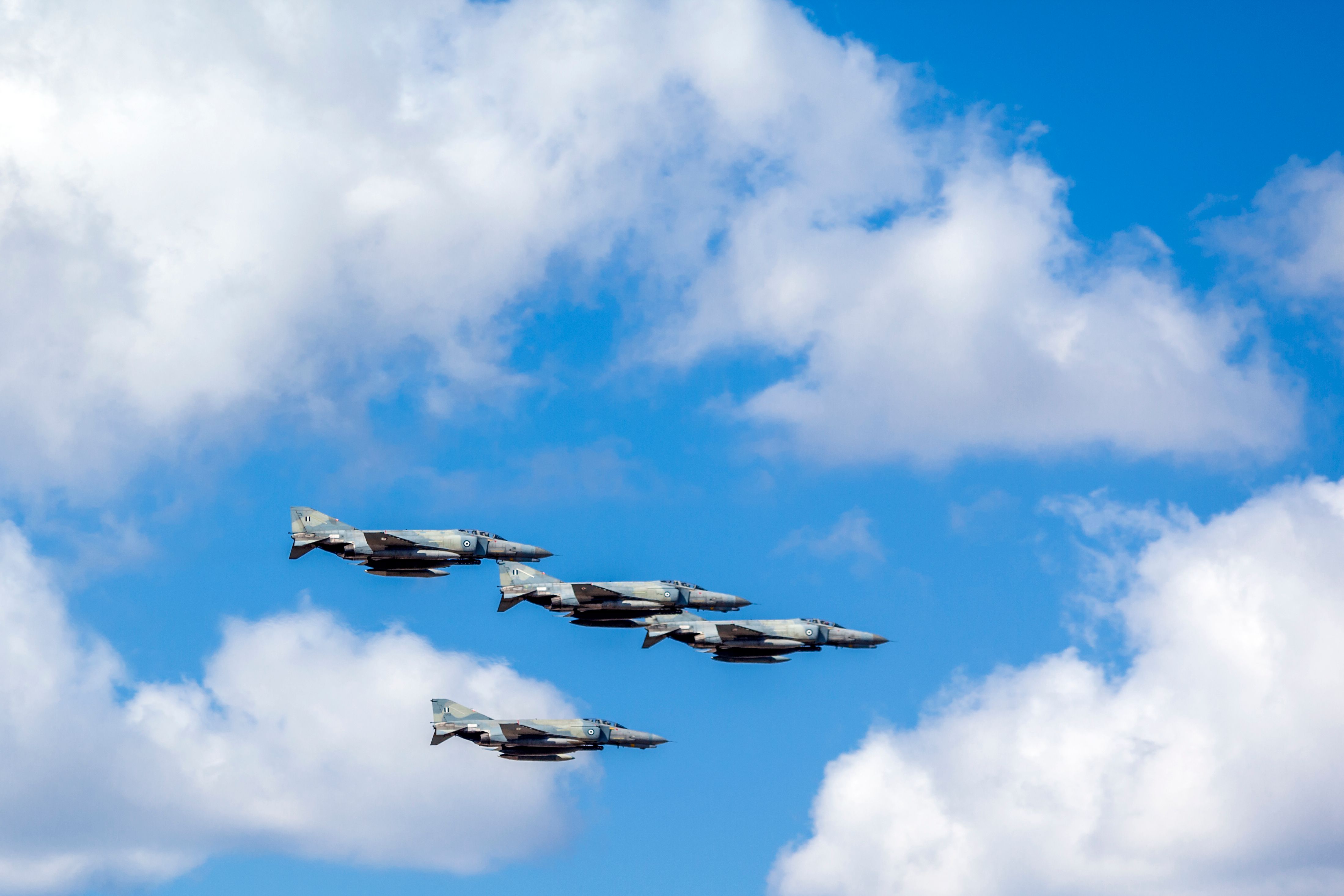 Four McDonnell Douglas F-4 Phantom II fighter jets flying in the sky.