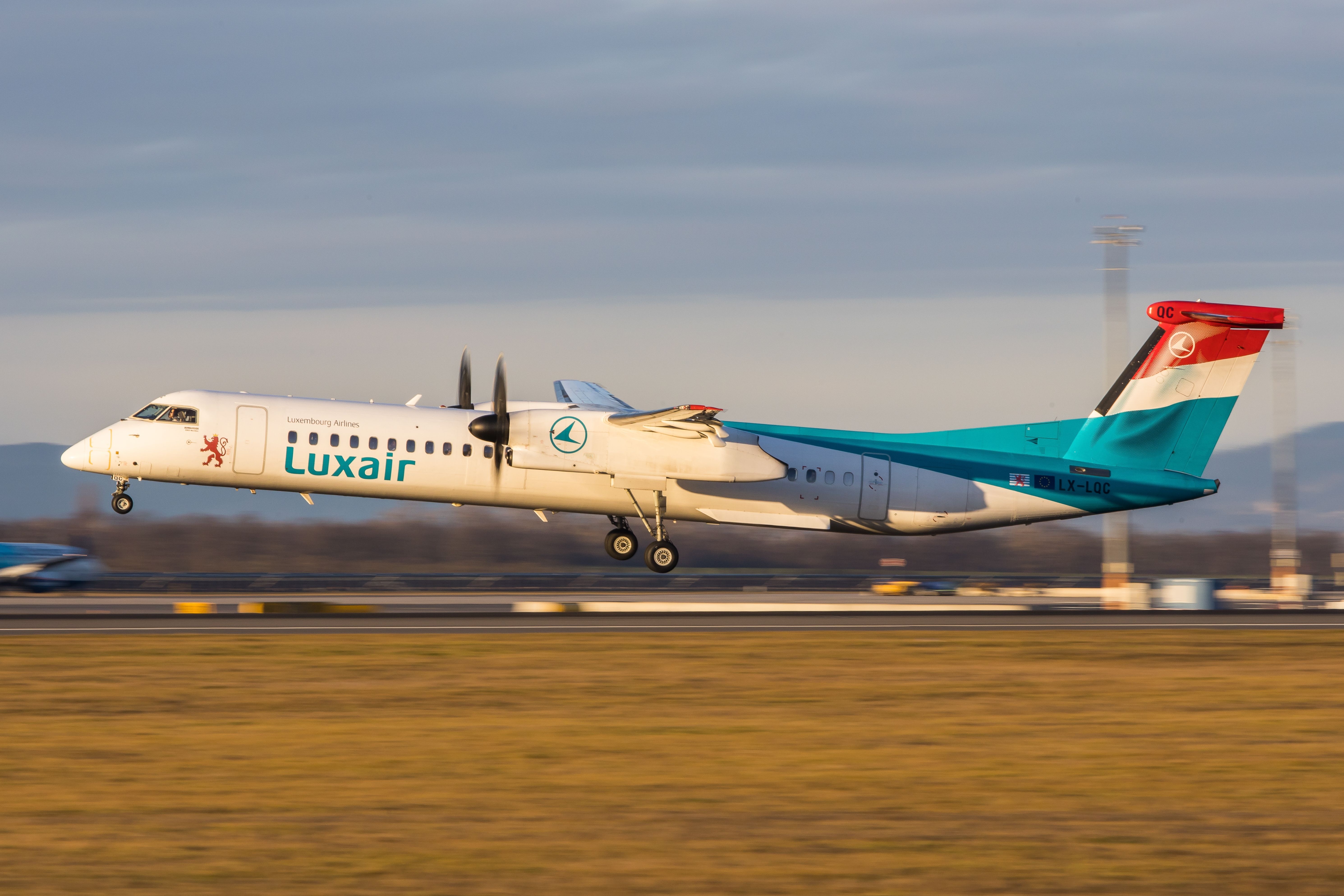 A Luxair Dash 8 about to land during sunrise.