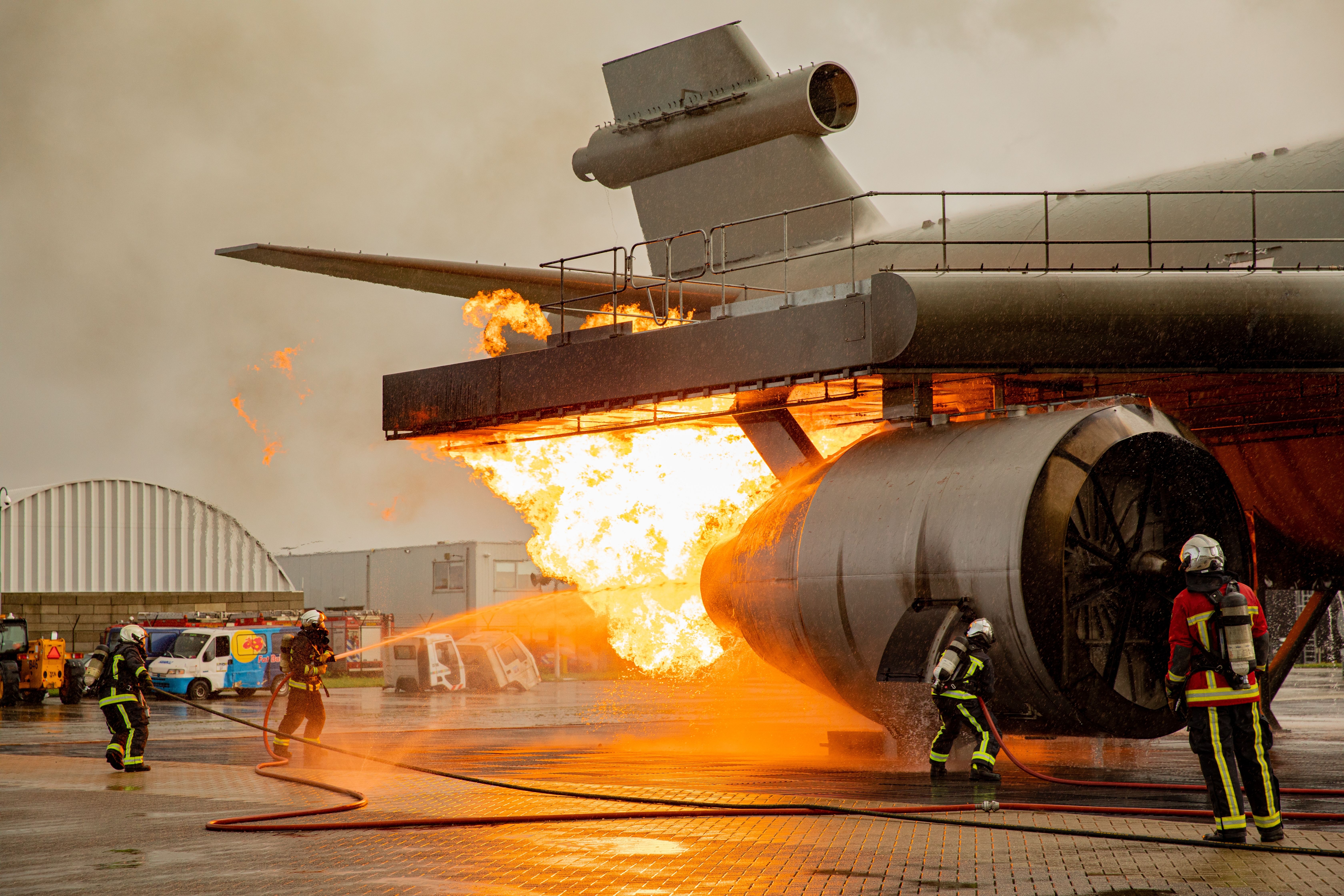 Firefighters spraying water on an engine that is on fire.