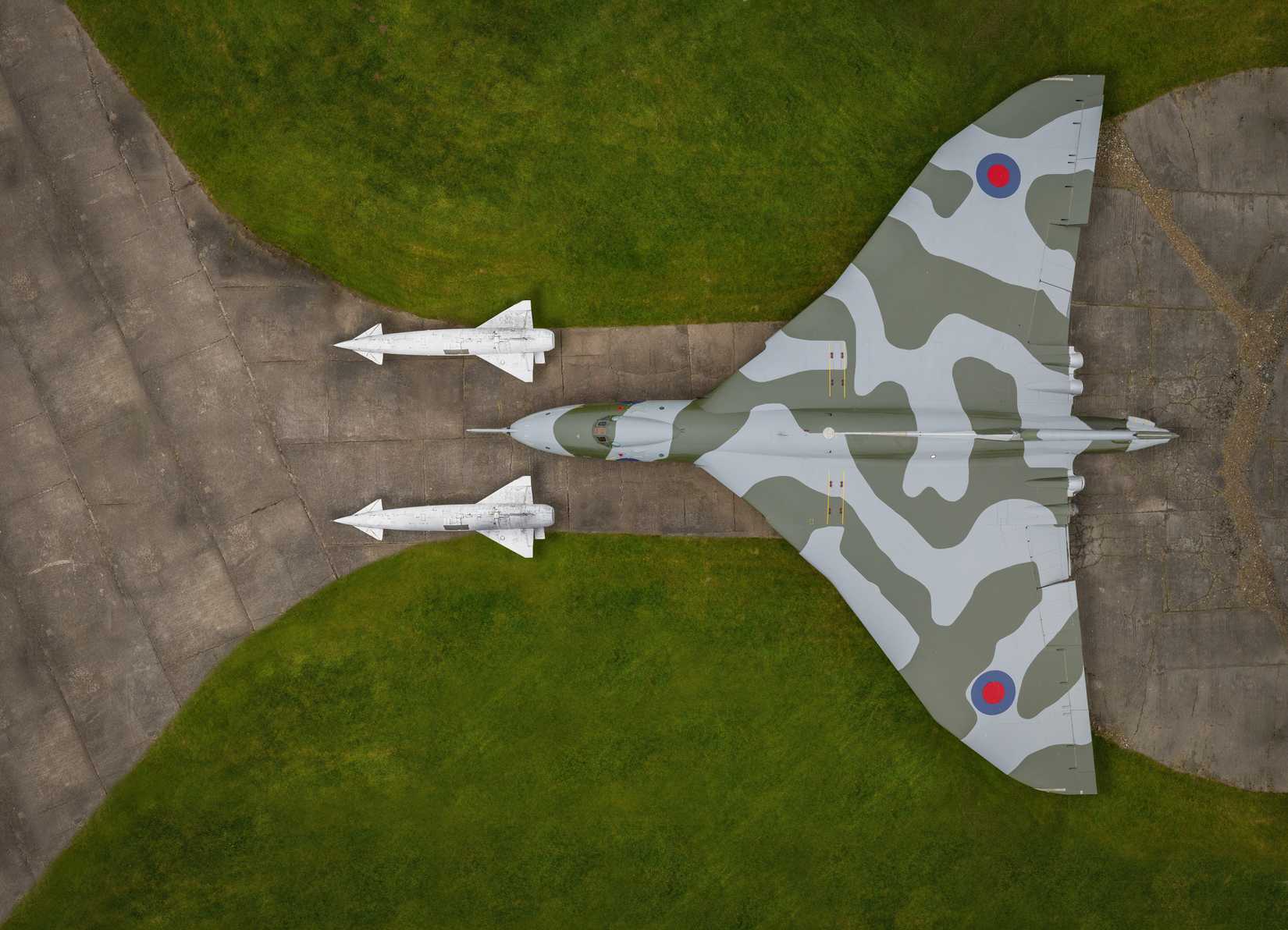 Two large missles sitting next to an Avro Vulcan.