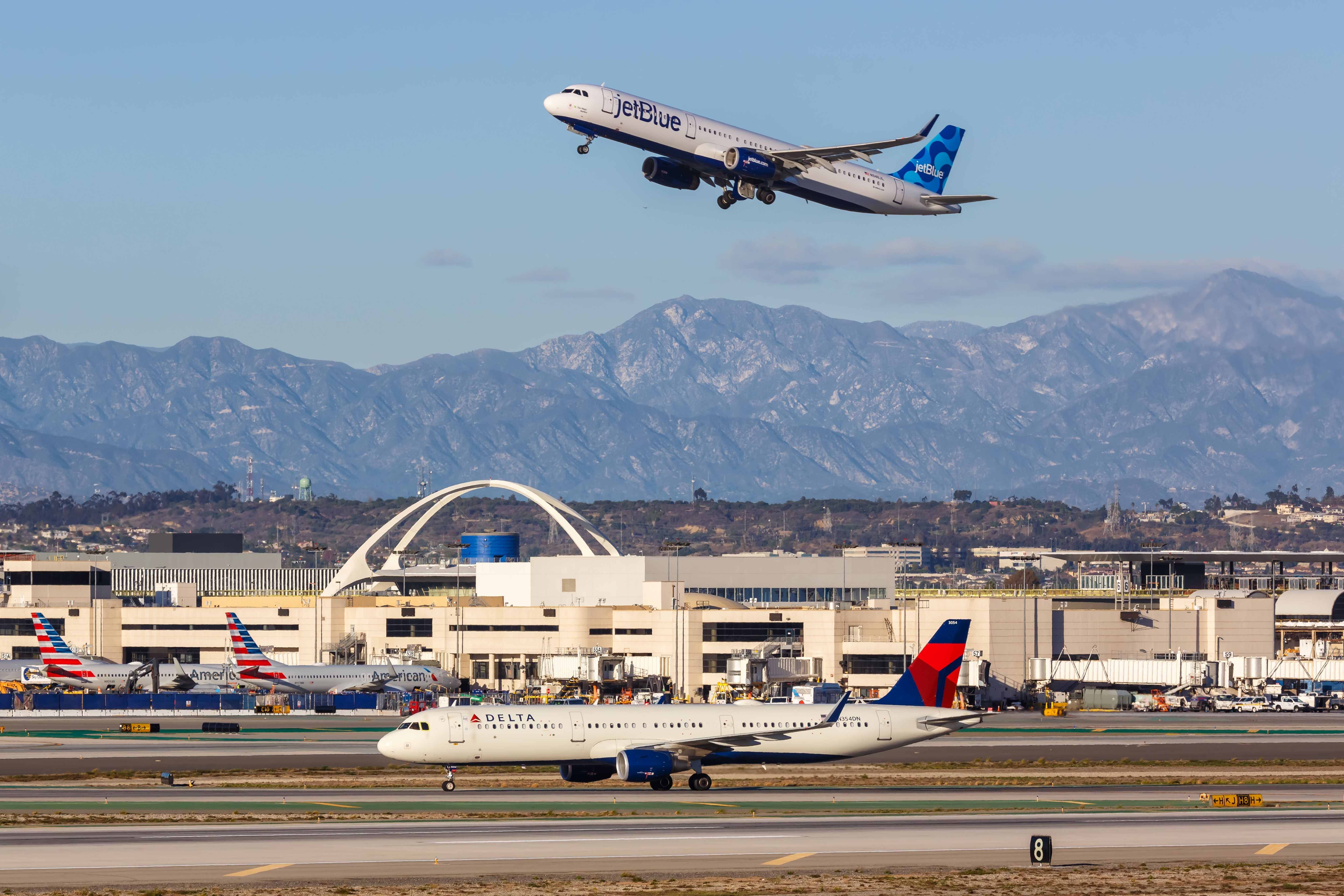 A Delta Air Lines Aircraft On a Taxiway Below a JetBlue Aircraft just after take off at Los Angeles Airport.