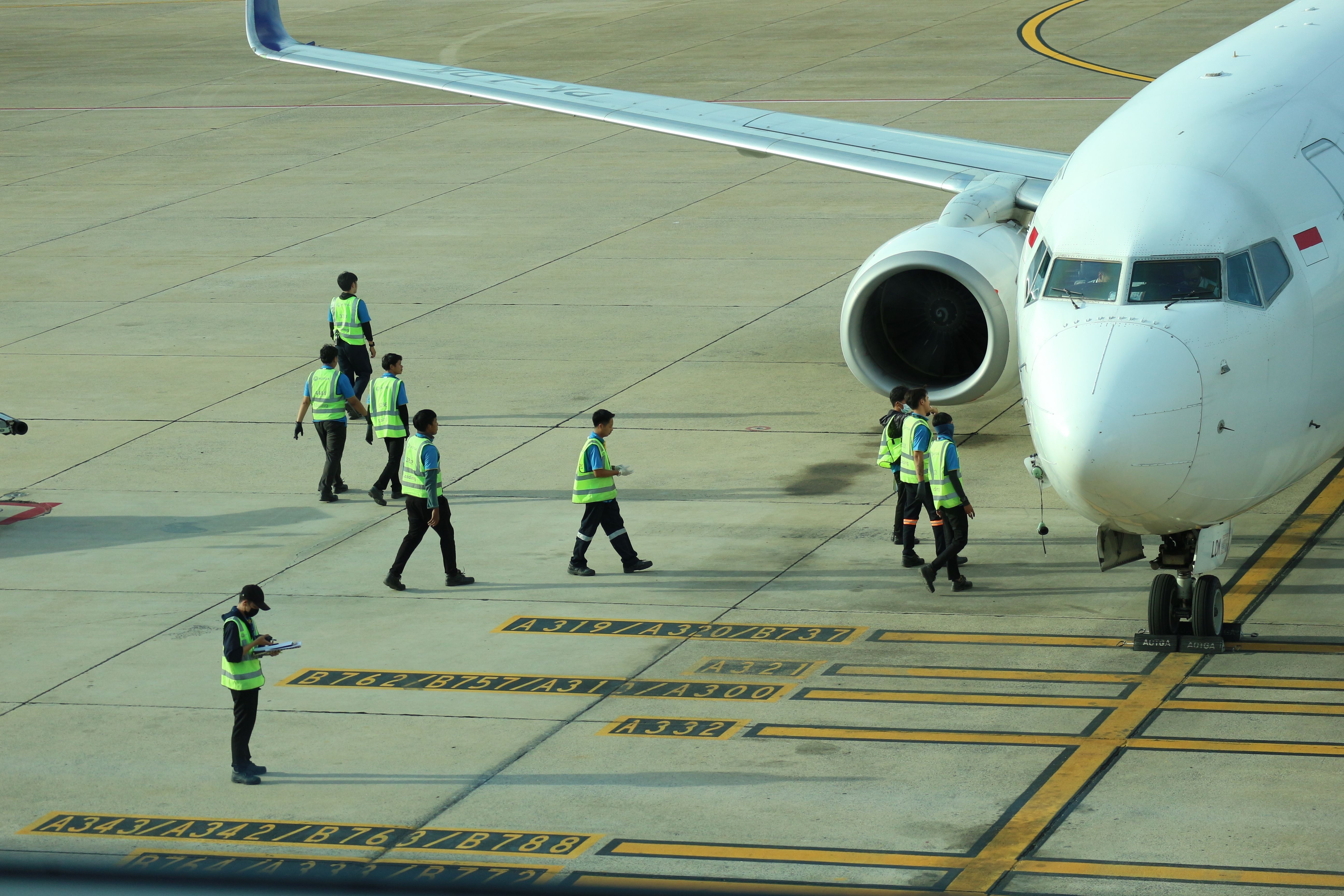 Several workers around an aircraft on the apron.