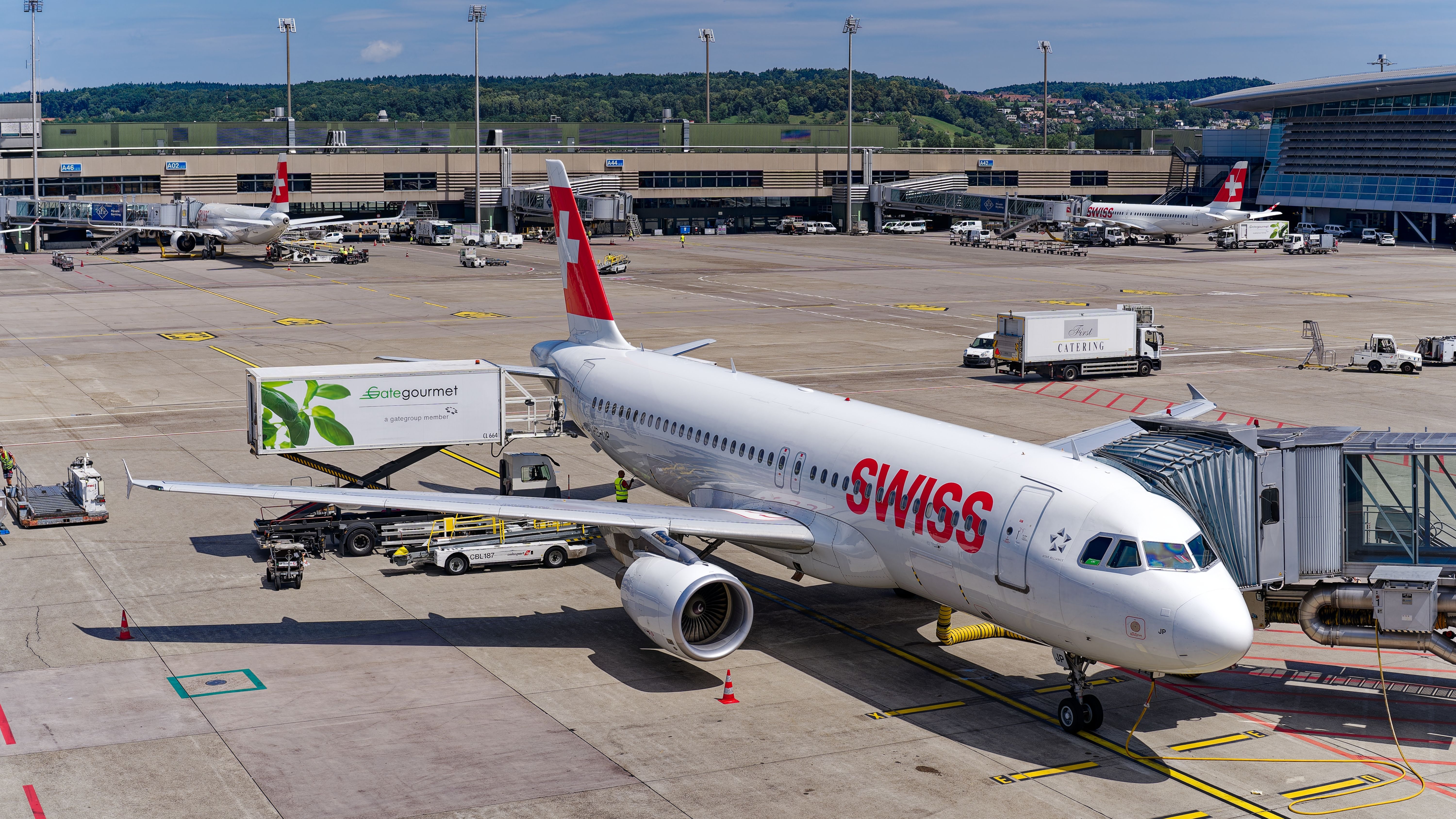 A Swiss aircraft parked with a catering truck parked next to it.