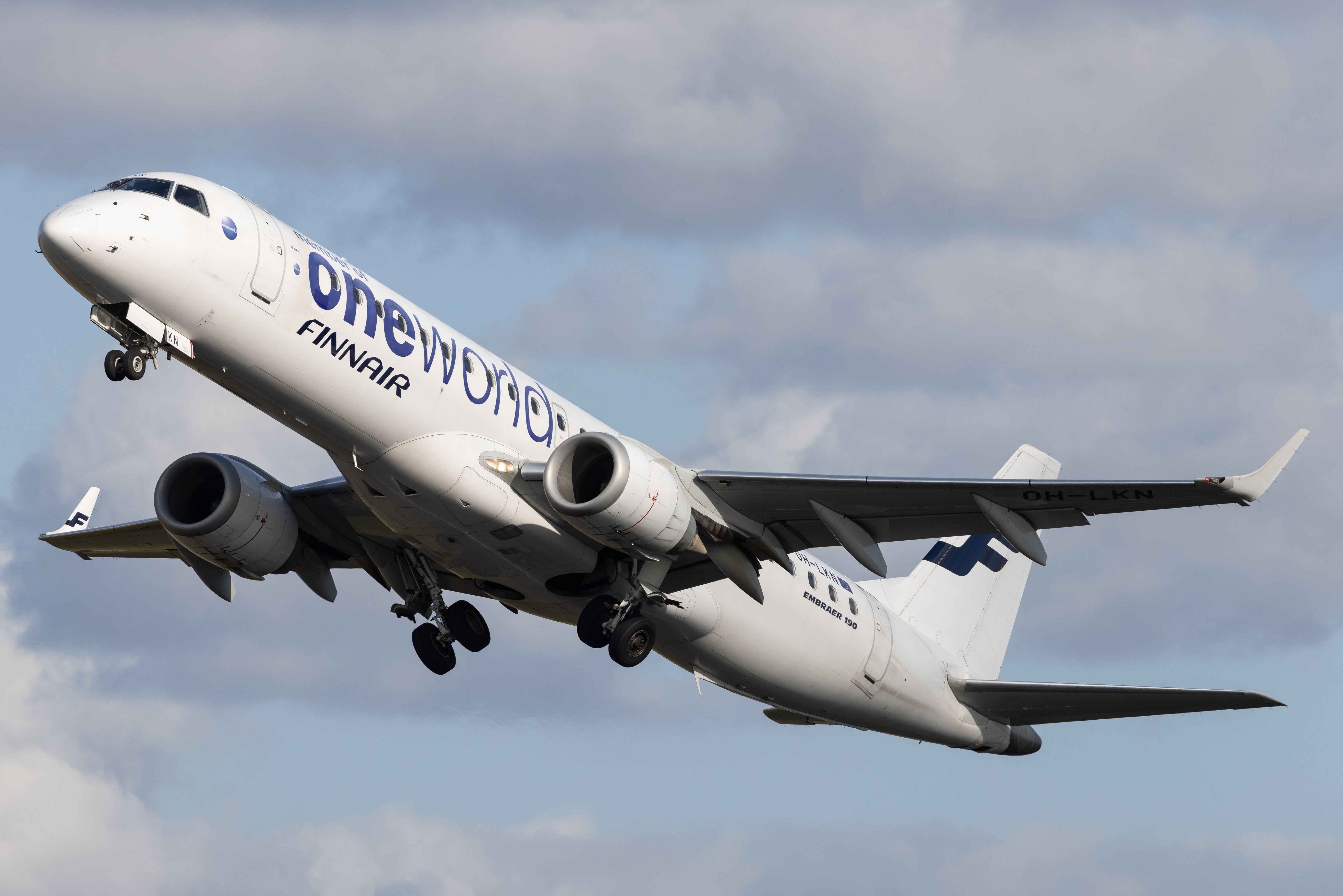 A Finnair Embraer E190 in OneWorld livery flying in the sky.