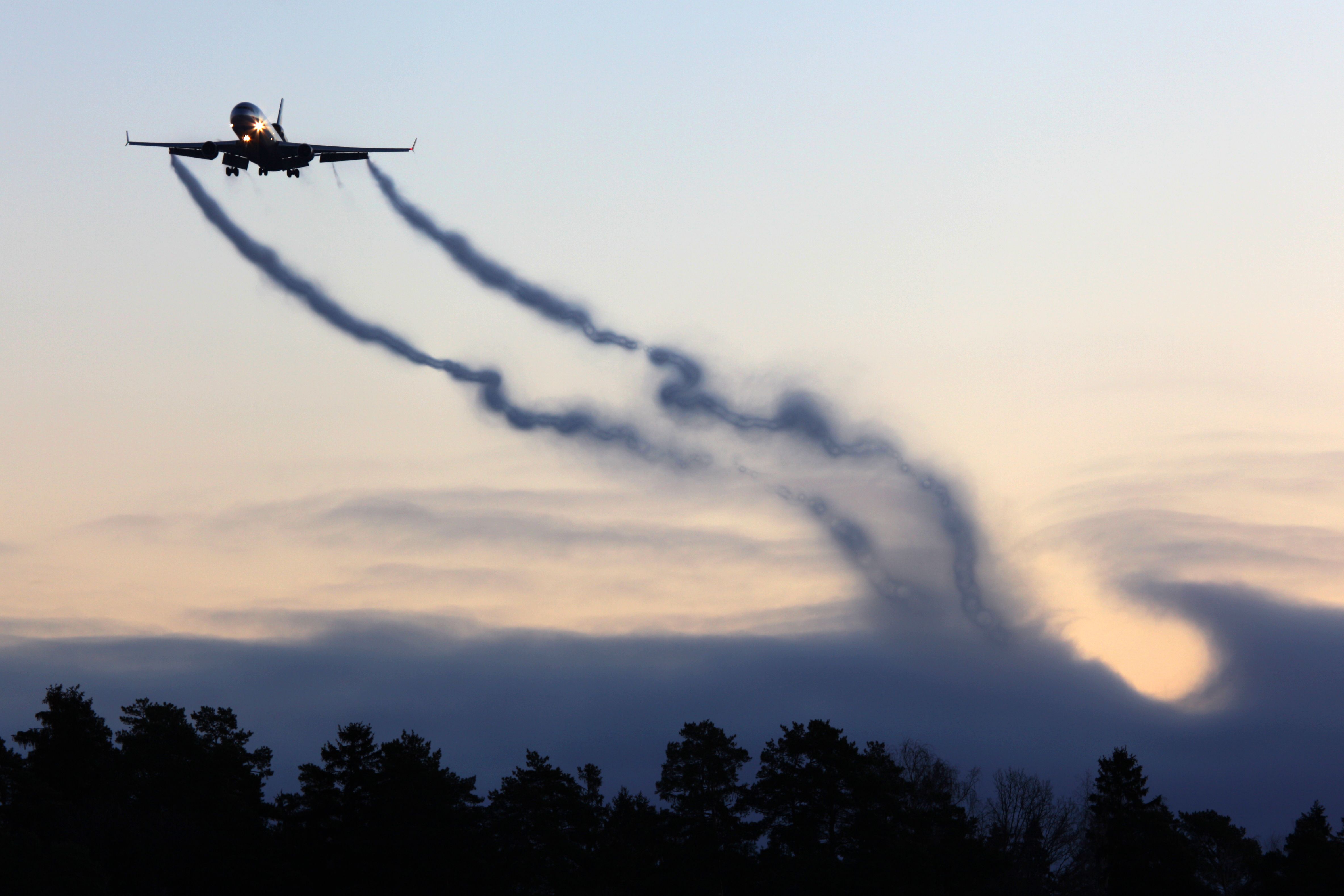 a McDonnell Douglas MD-11 Flying in the sky with wingtip vortices easily seen.