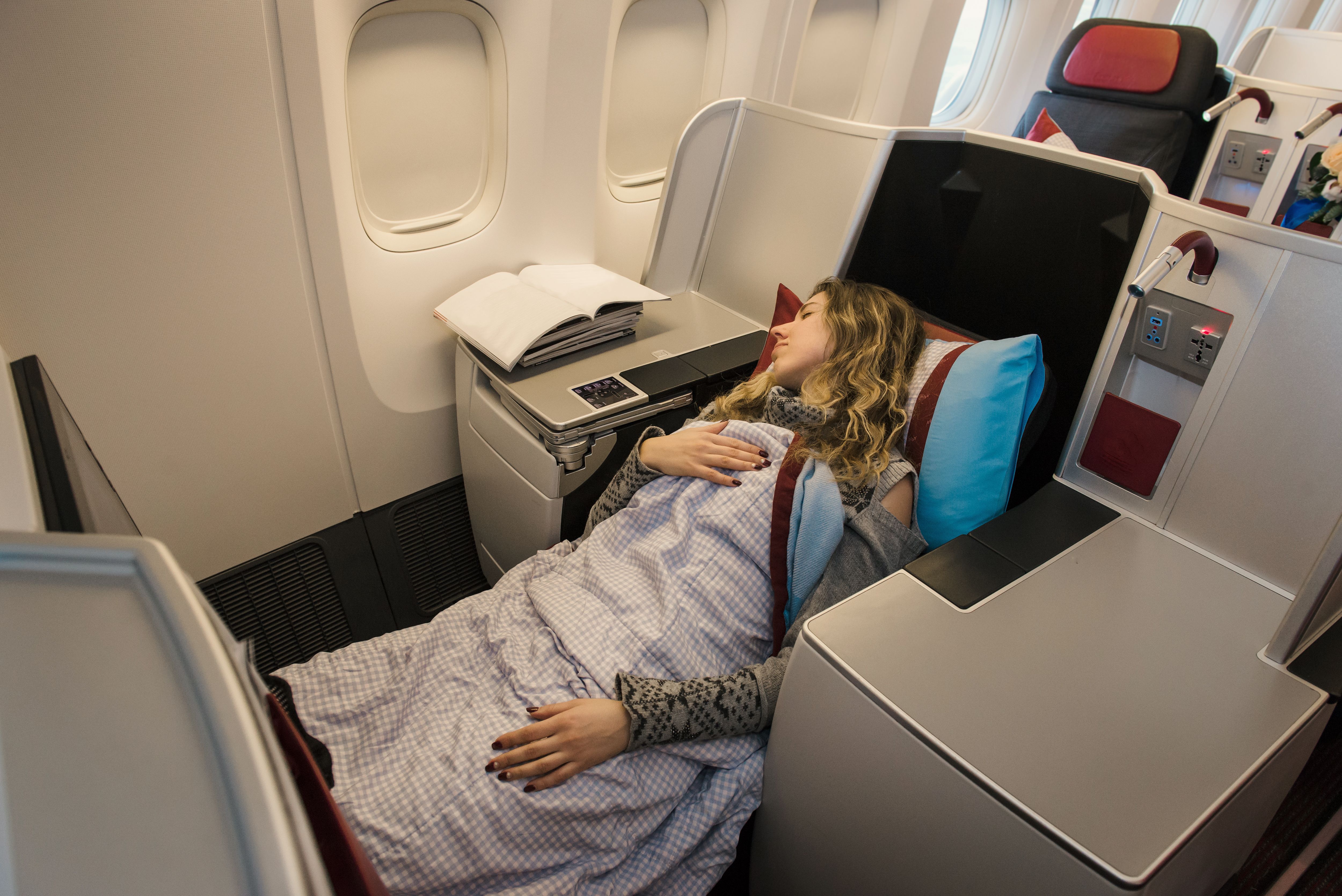 A passeneger sleeping in a business class throne seat.