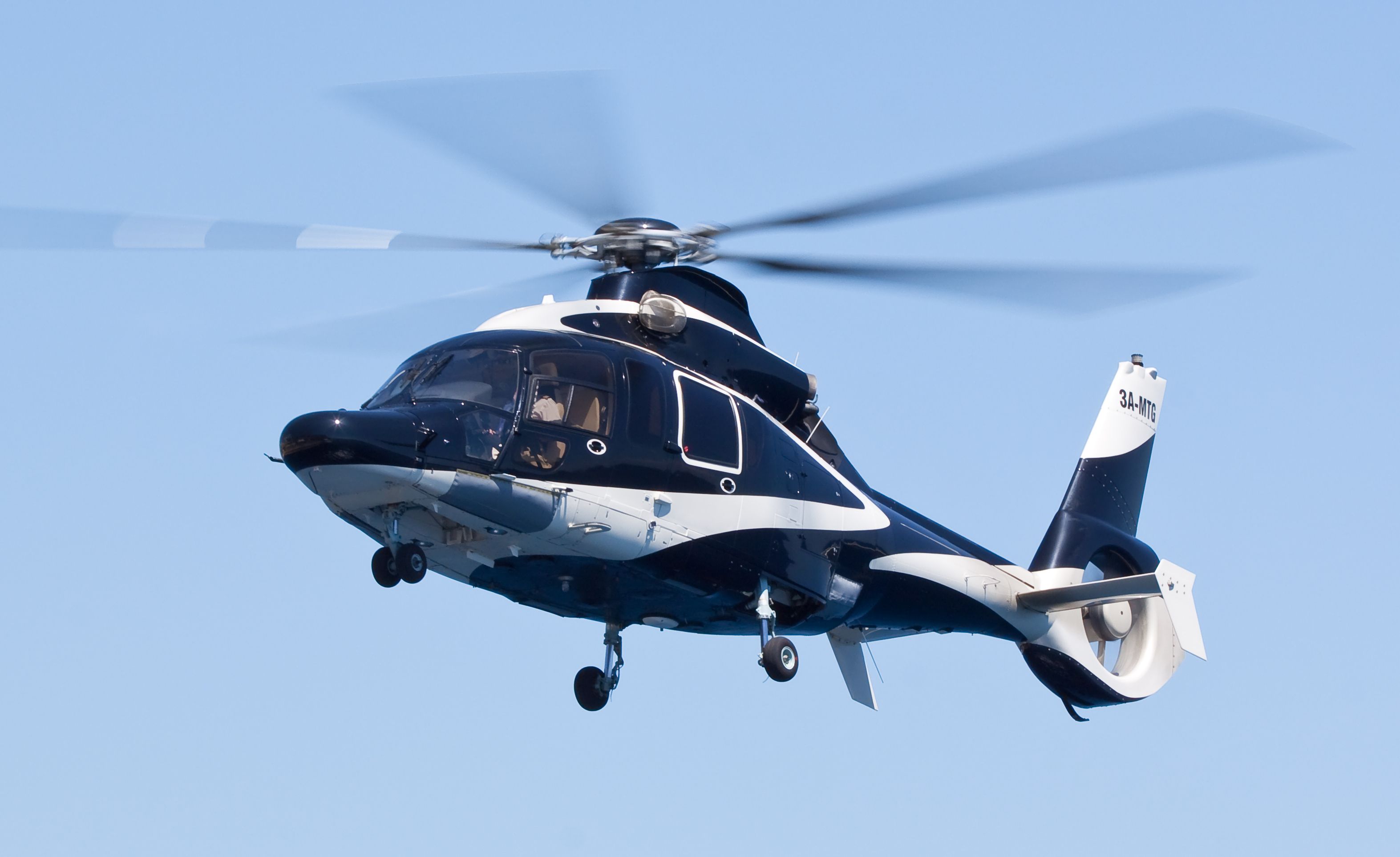 An Airbus H155 helicopter flying in the sky.