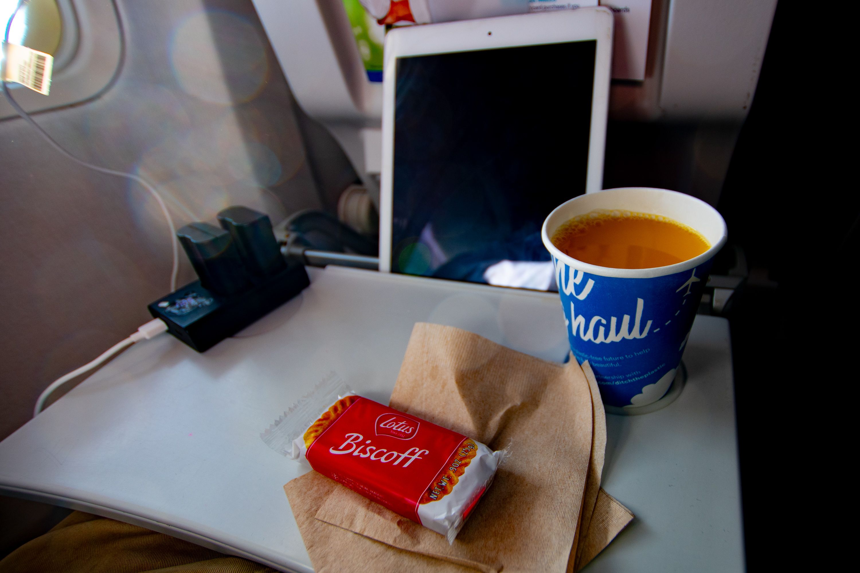 My Seat-Desk at Work on the 737-700 with iPad, coffee, charger and Biscoff