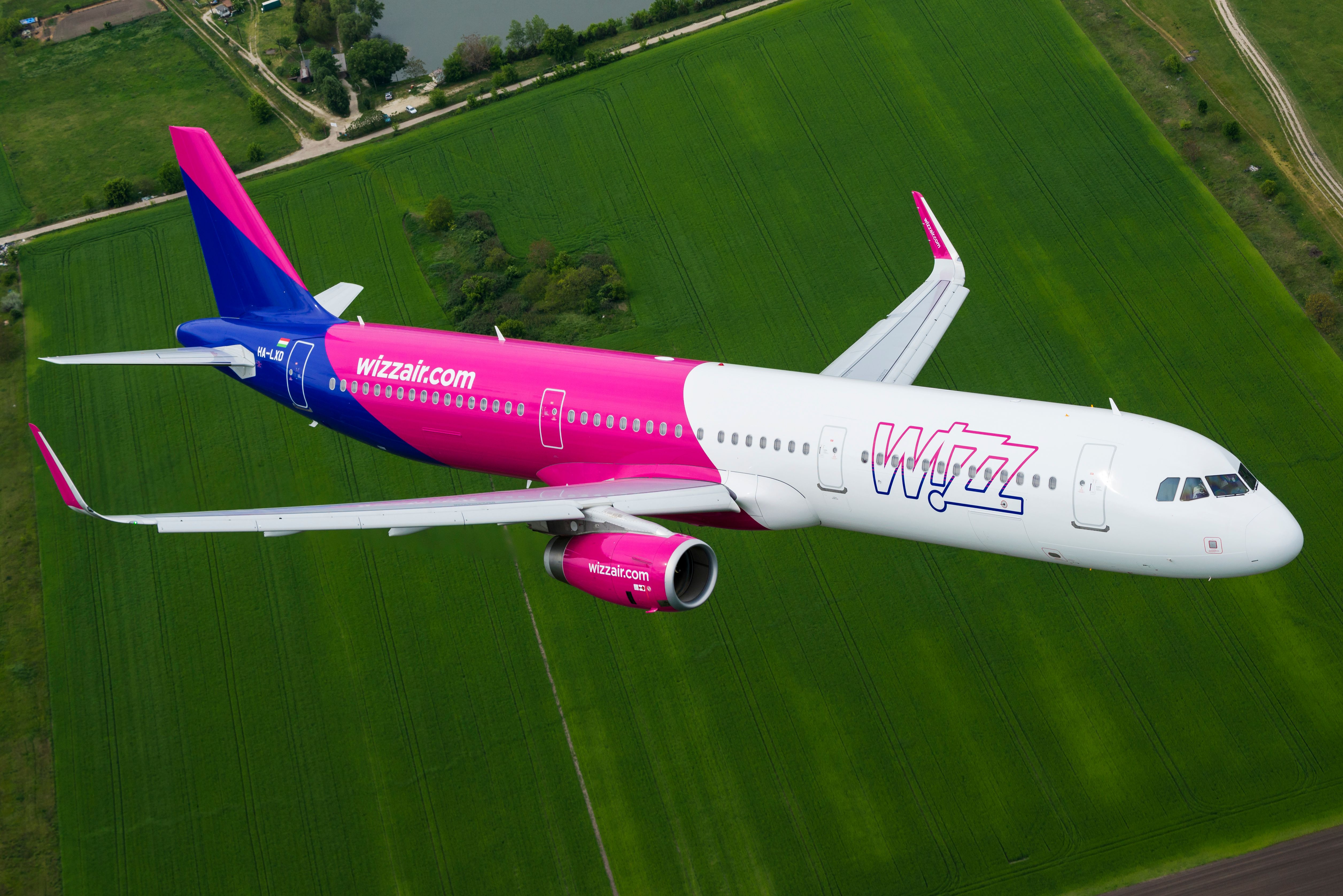 Wizz Air Airbus A321 flying over a green field