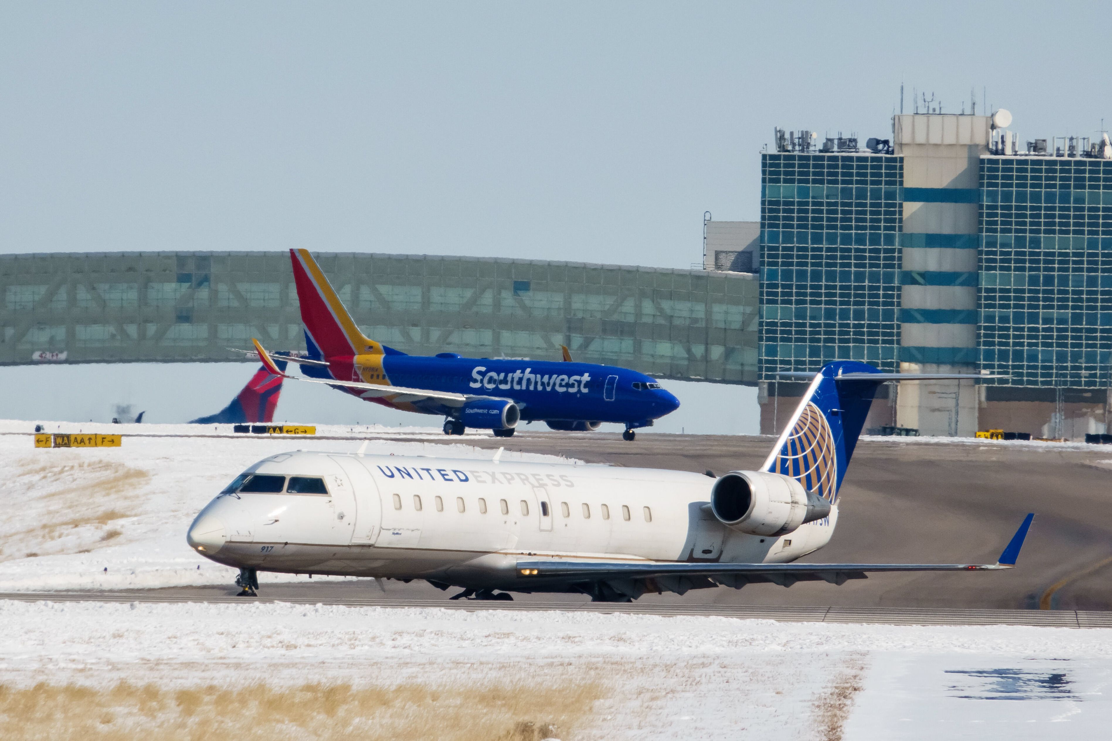 A United Express plane in front of a Southwest Airlines jet and the tails of Delta Air Lines and Frontier Airlines.