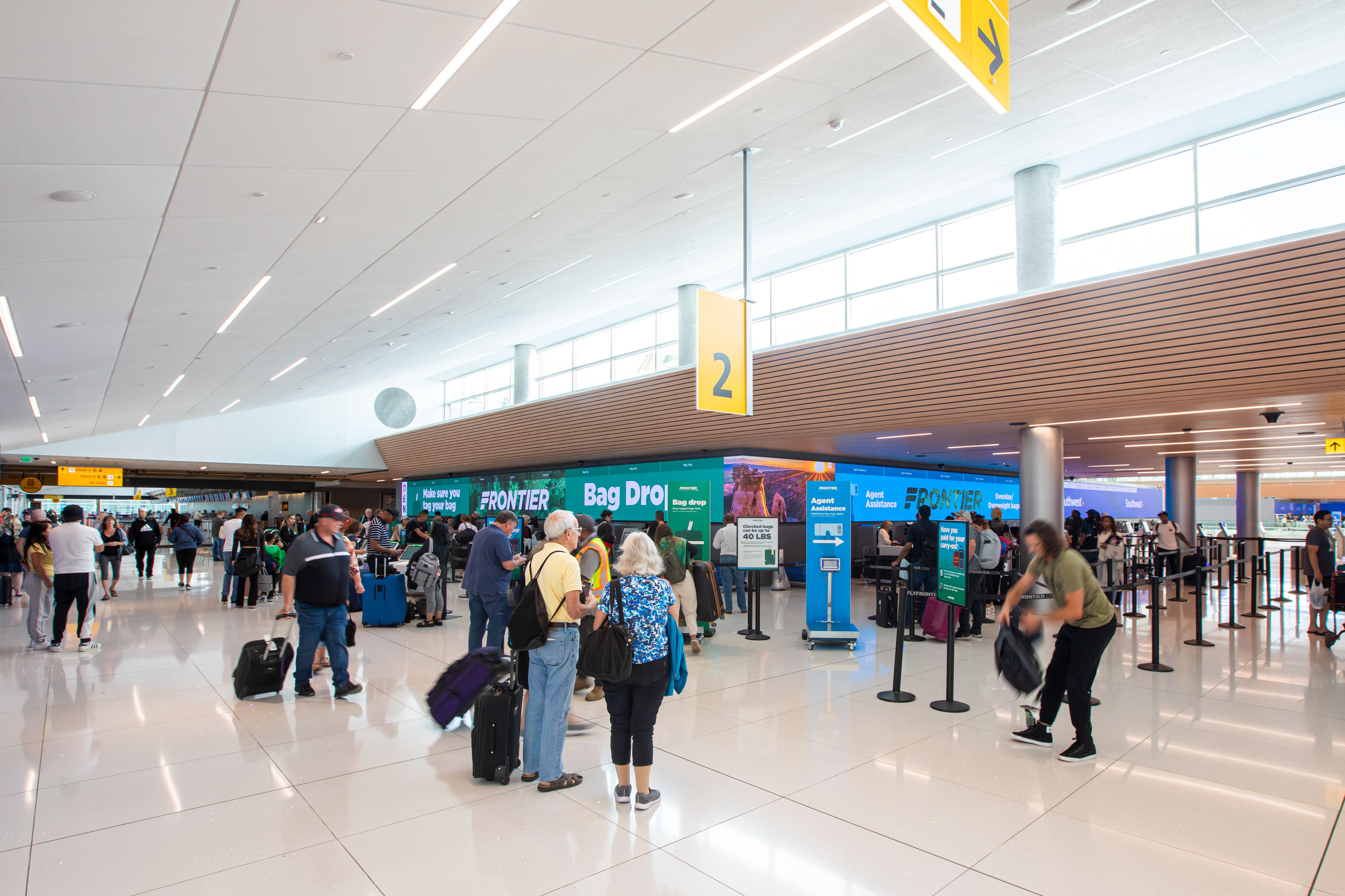 Several Passengers Congregating Near The Frontier Check-In Area At Denver International Airport.