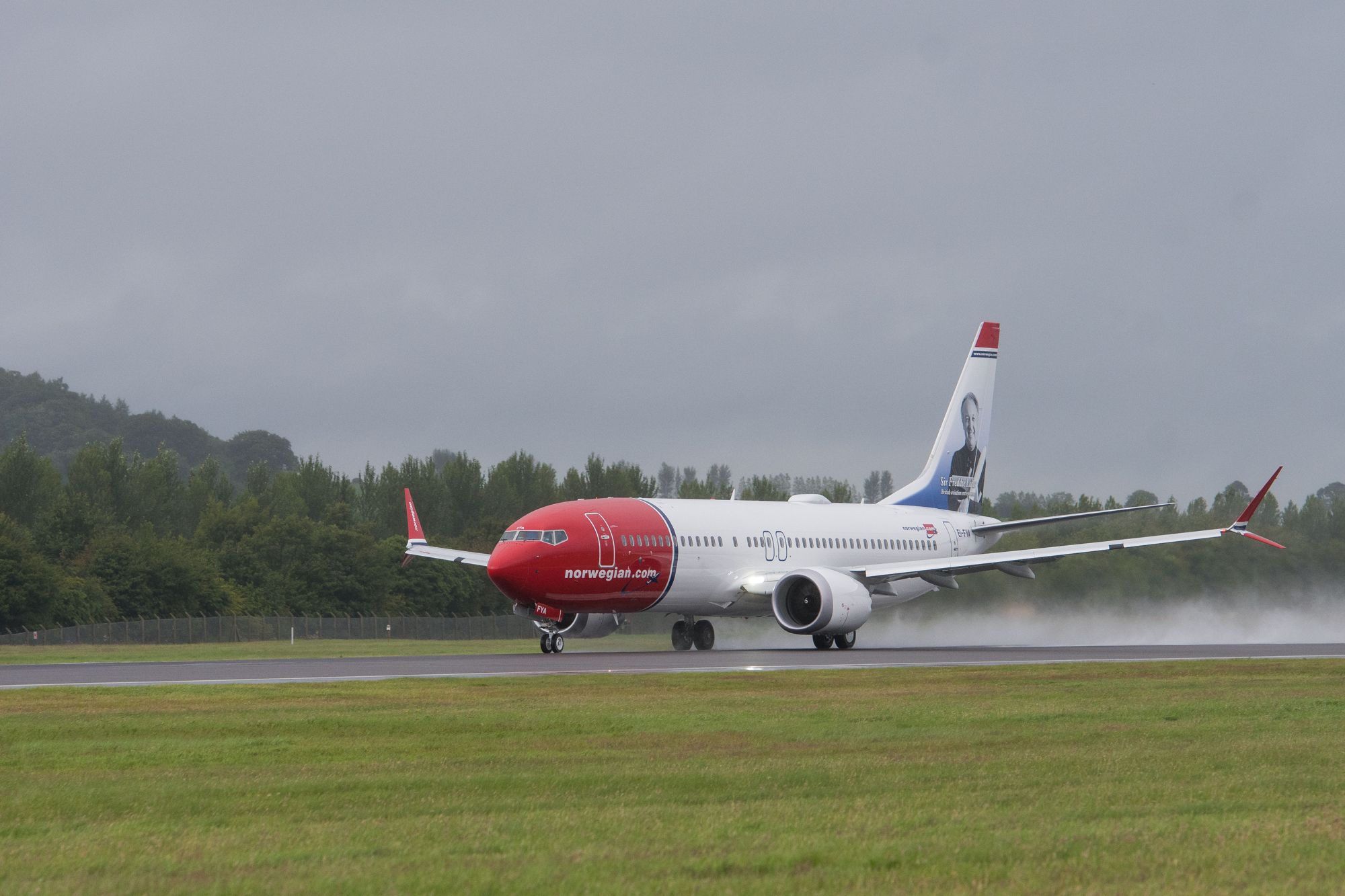 A Norwegian aircraft on a wet runway.